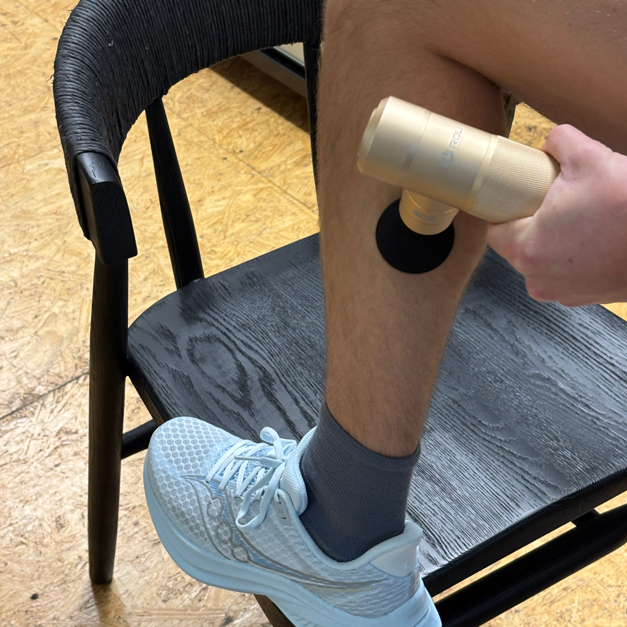 closeup of person using a Roll Recovery massage gun on calf