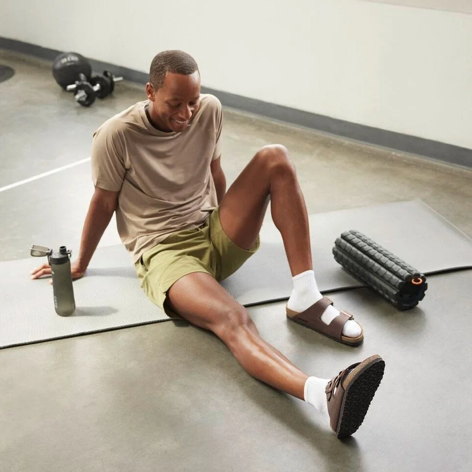 man wearing Birkenstock sandals and using a foam roller