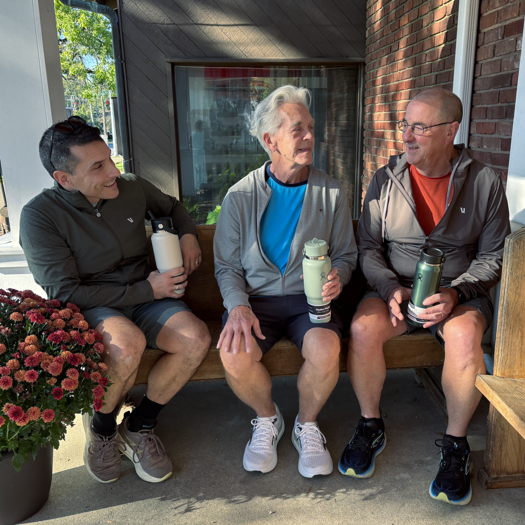 three men talking on bench wearing Vuori apparel