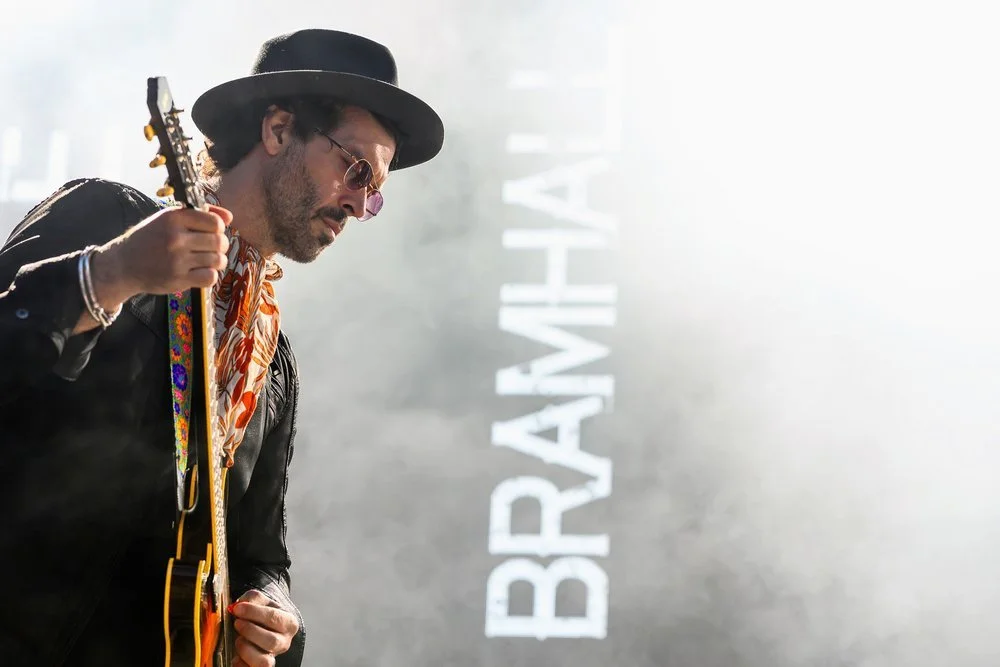 Musicien jouant de la guitare sur scène lors d’un concert avec éclairages artistiques.