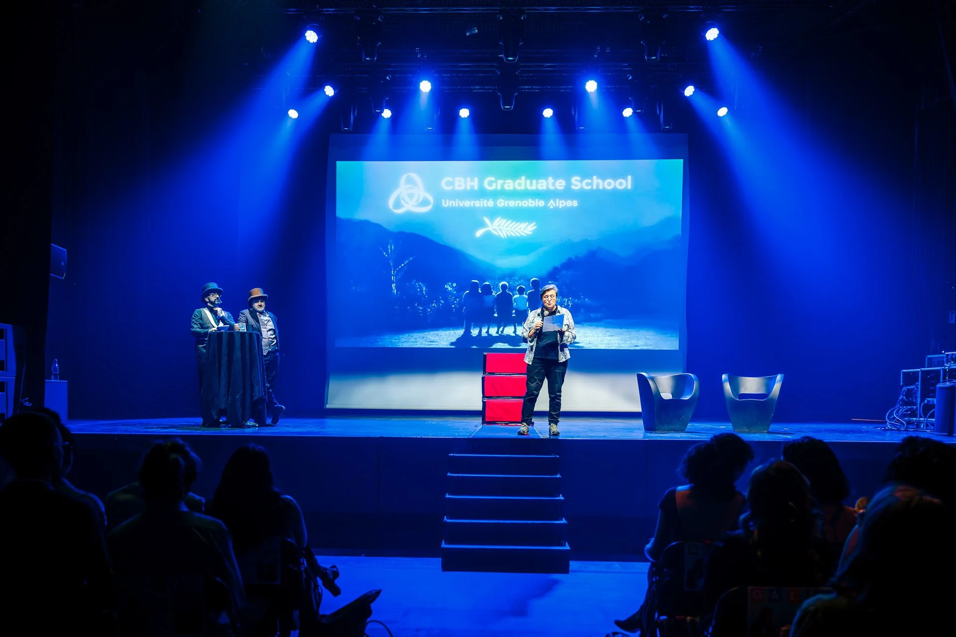 Scène du gala CBH Graduate School avec les intervenants et projection du visuel de l’Université Grenoble Alpes