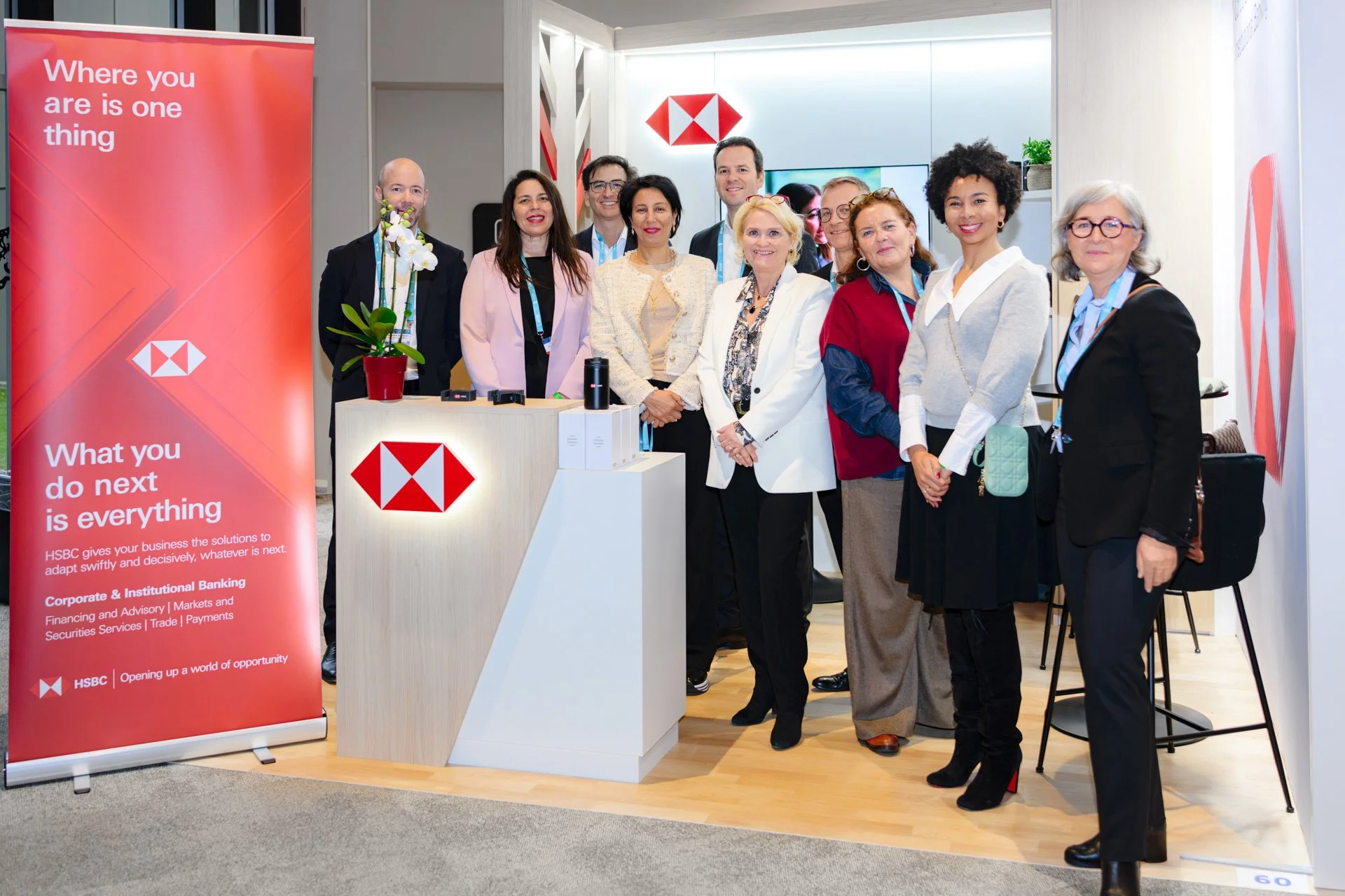 Équipe HSBC réunie sur leur stand, devant le panneau corporate rouge, pendant les Journées de l’AFTE 2025.