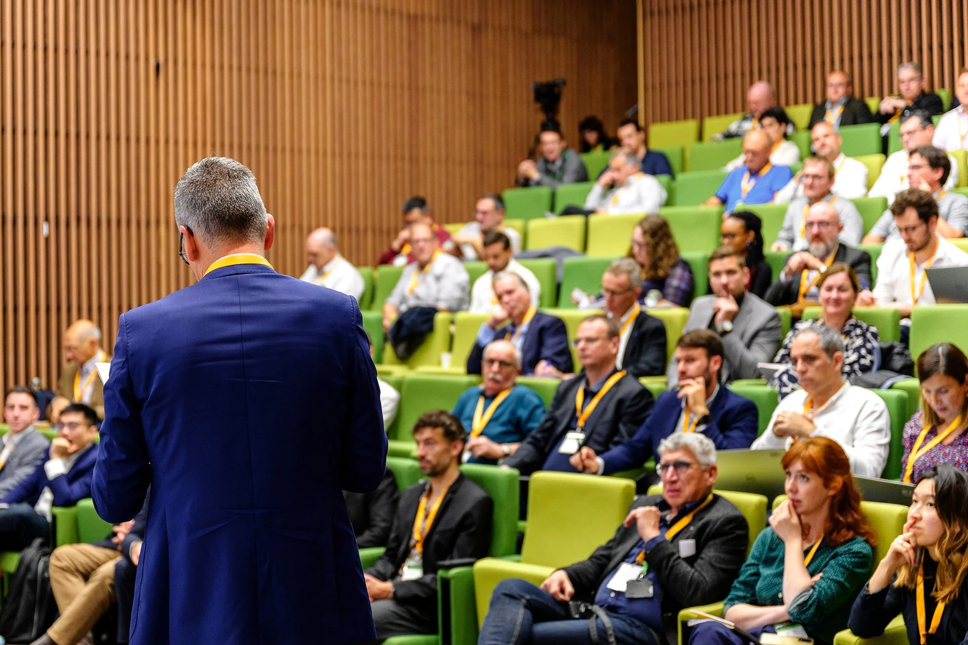 Vue arrière d’un intervenant face au public lors d’un séminaire d’entreprise photographié