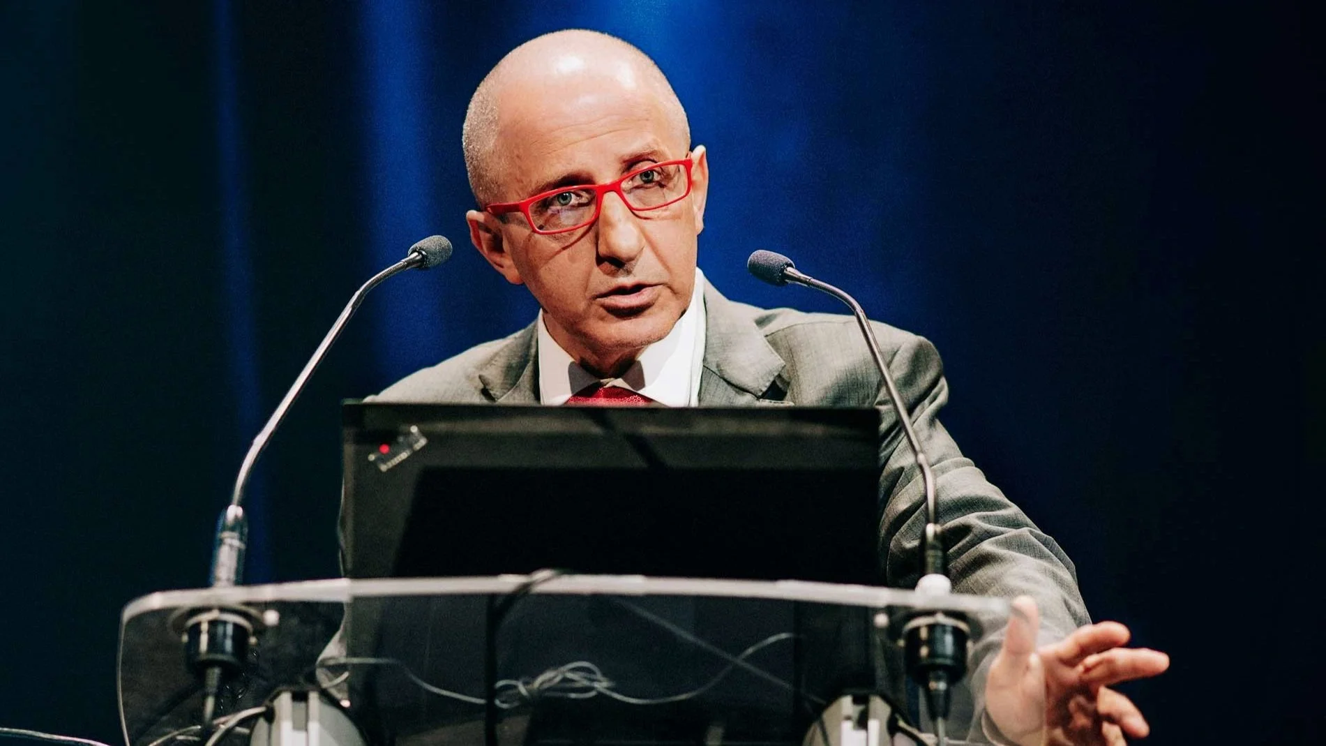Intervenant au pupitre lors d’une conférence professionnelle.