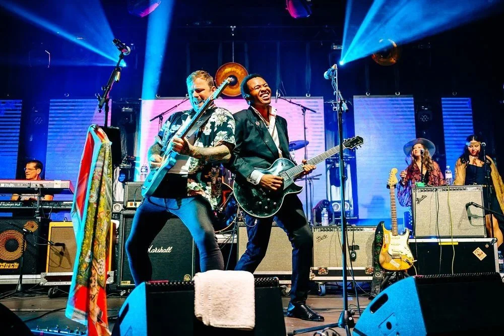 Deux guitaristes sur scène, énergie partagée et complicité captées en photo live.