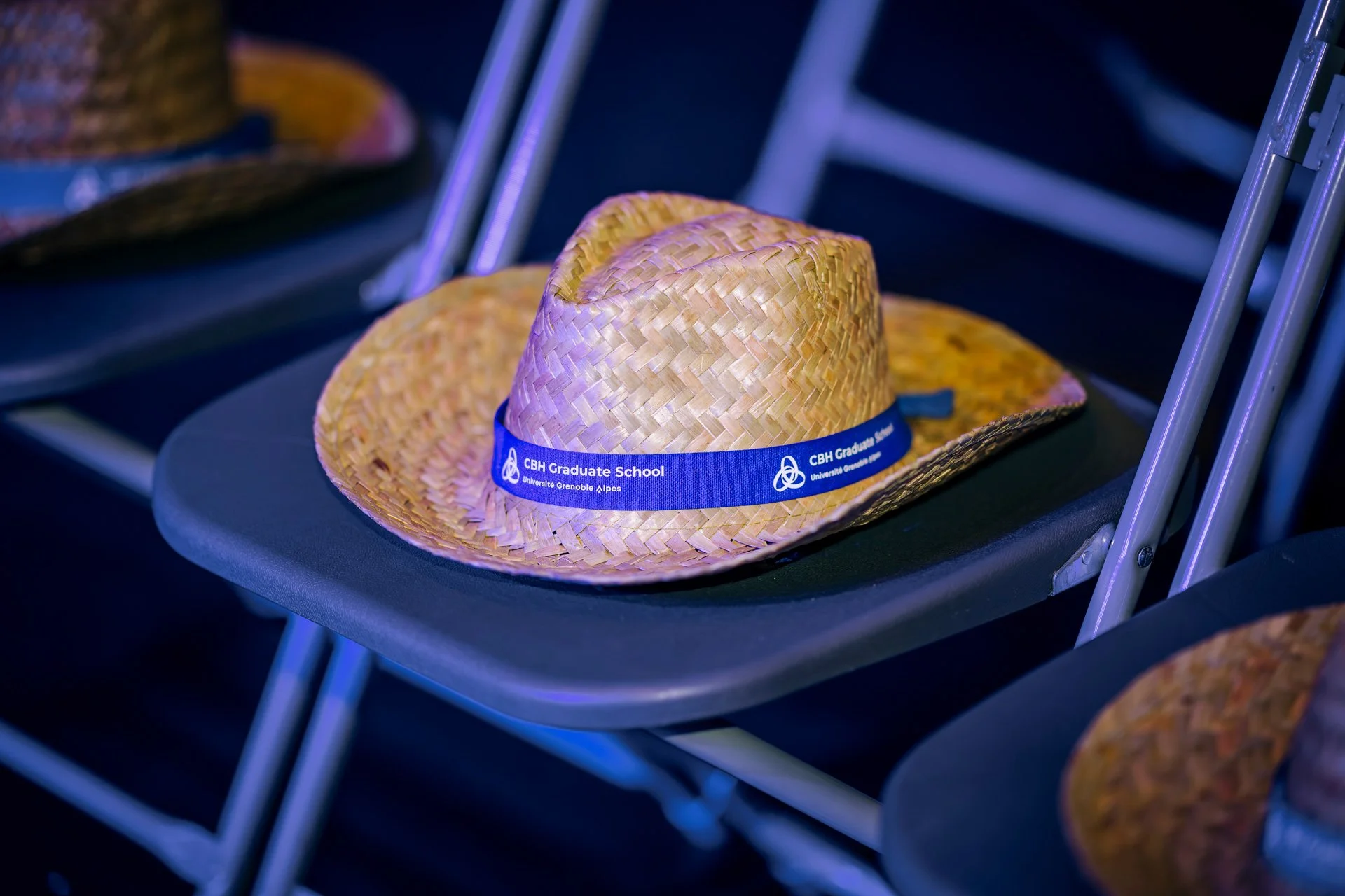 Chapeau en paille siglé CBH Graduate School posé sur une chaise lors du gala UGA à La Belle Électrique