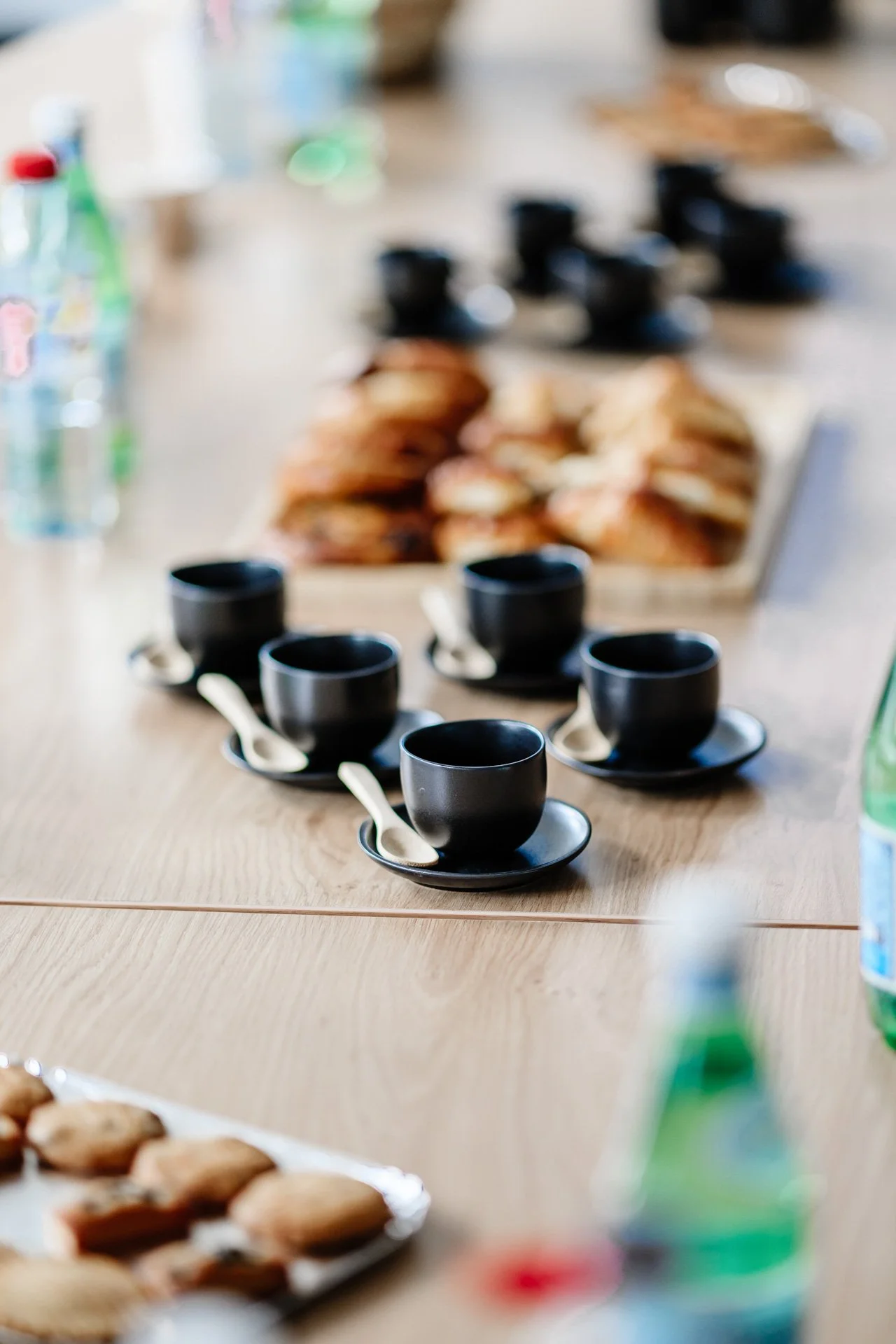 Table de petit-déjeuner dressée pour l’accueil des invités de l’inauguration Heliup, avec tasses noires, viennoiseries et bouteilles d’eau.