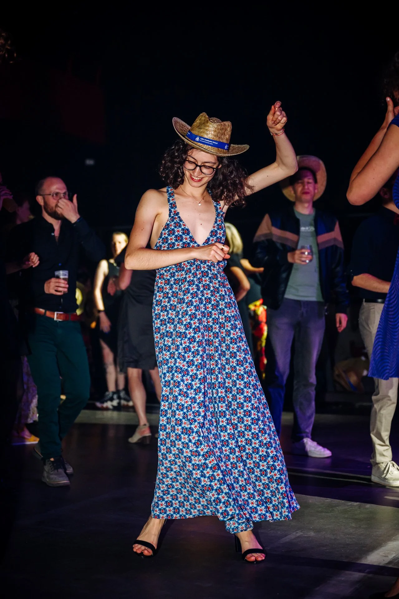 Étudiante portant un chapeau de paille en train de danser durant la soirée festive de la Graduate School CBH à Grenoble.