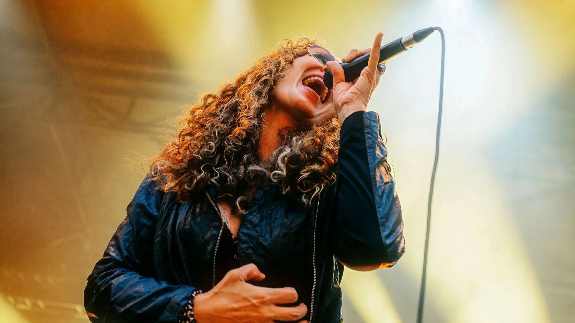 Chanteuse en pleine performance sur scène lors d’un concert, lumière intense et énergie live captées en reportage photo.