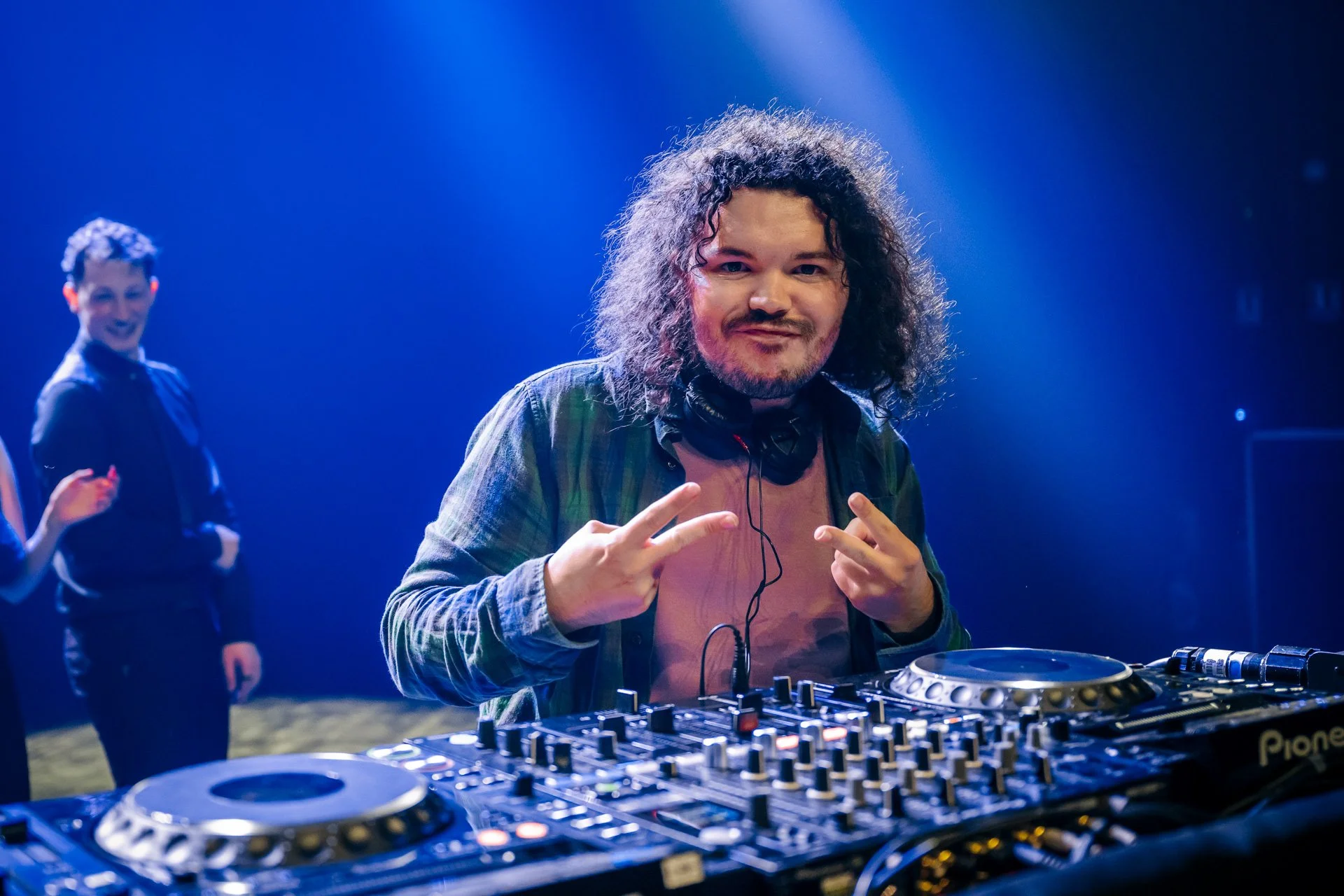 DJ en pleine performance lors de la soirée de la Graduate School CBH à Grenoble, éclairé par des lumières bleues sur scène.