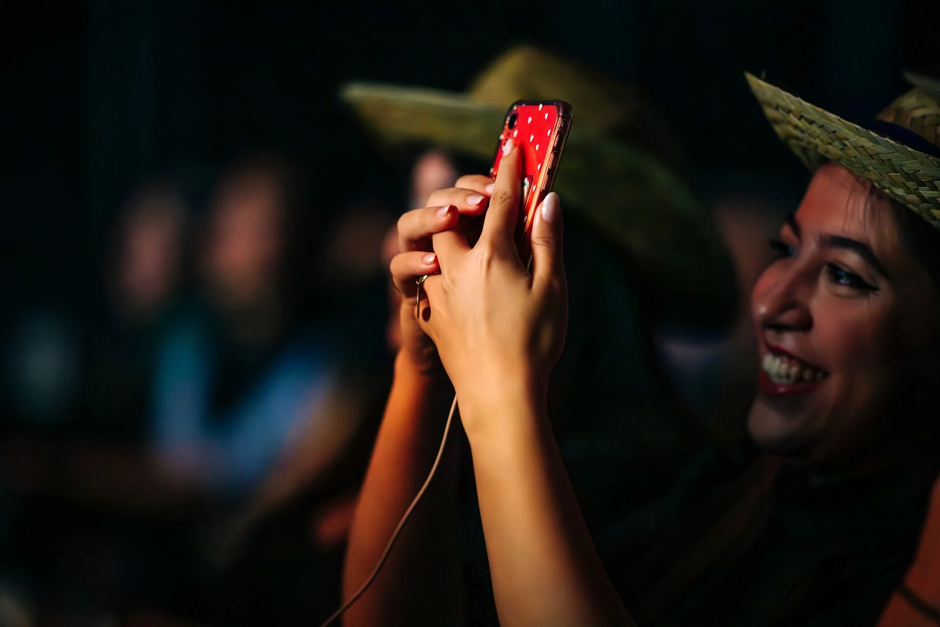 Invitée du gala CBH Graduate School souriante, en train de filmer la scène avec son smartphone pendant la soirée à la Belle Électrique.