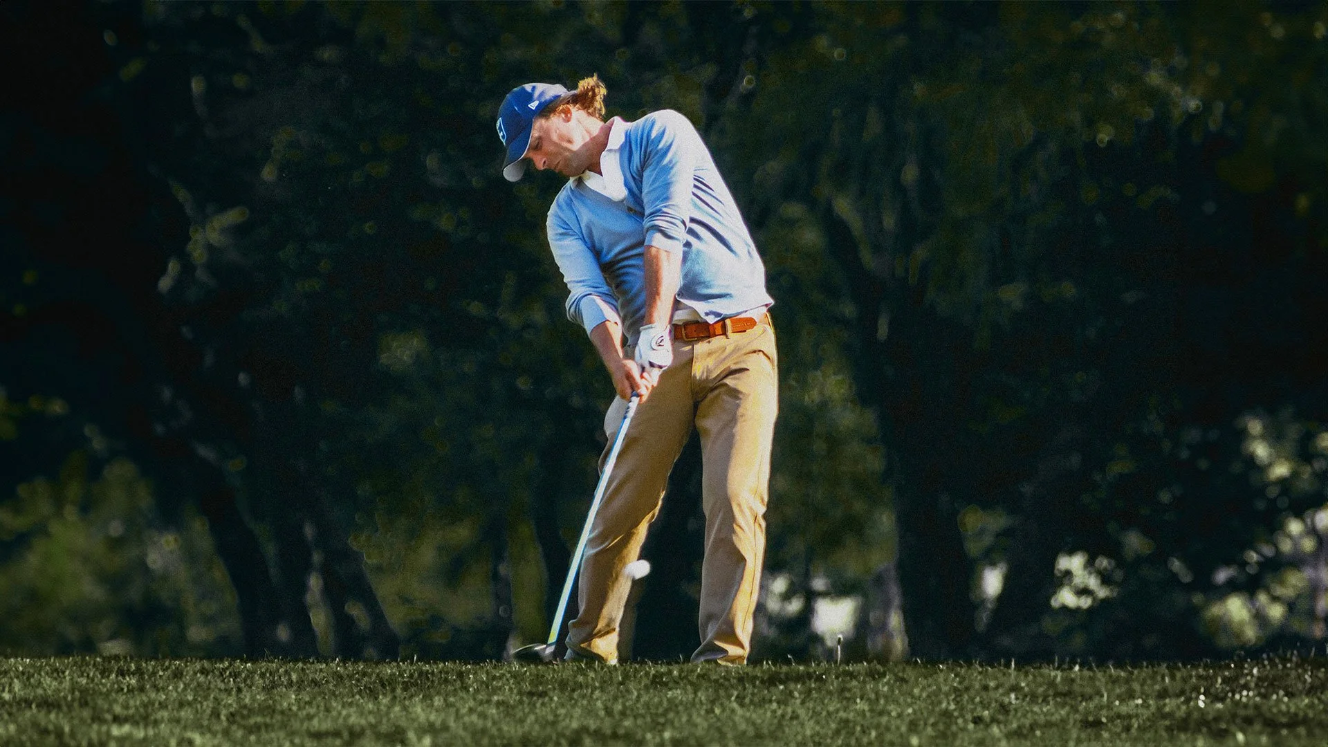 Golfeur en plein swing sur un terrain de golf, action sportive captée.