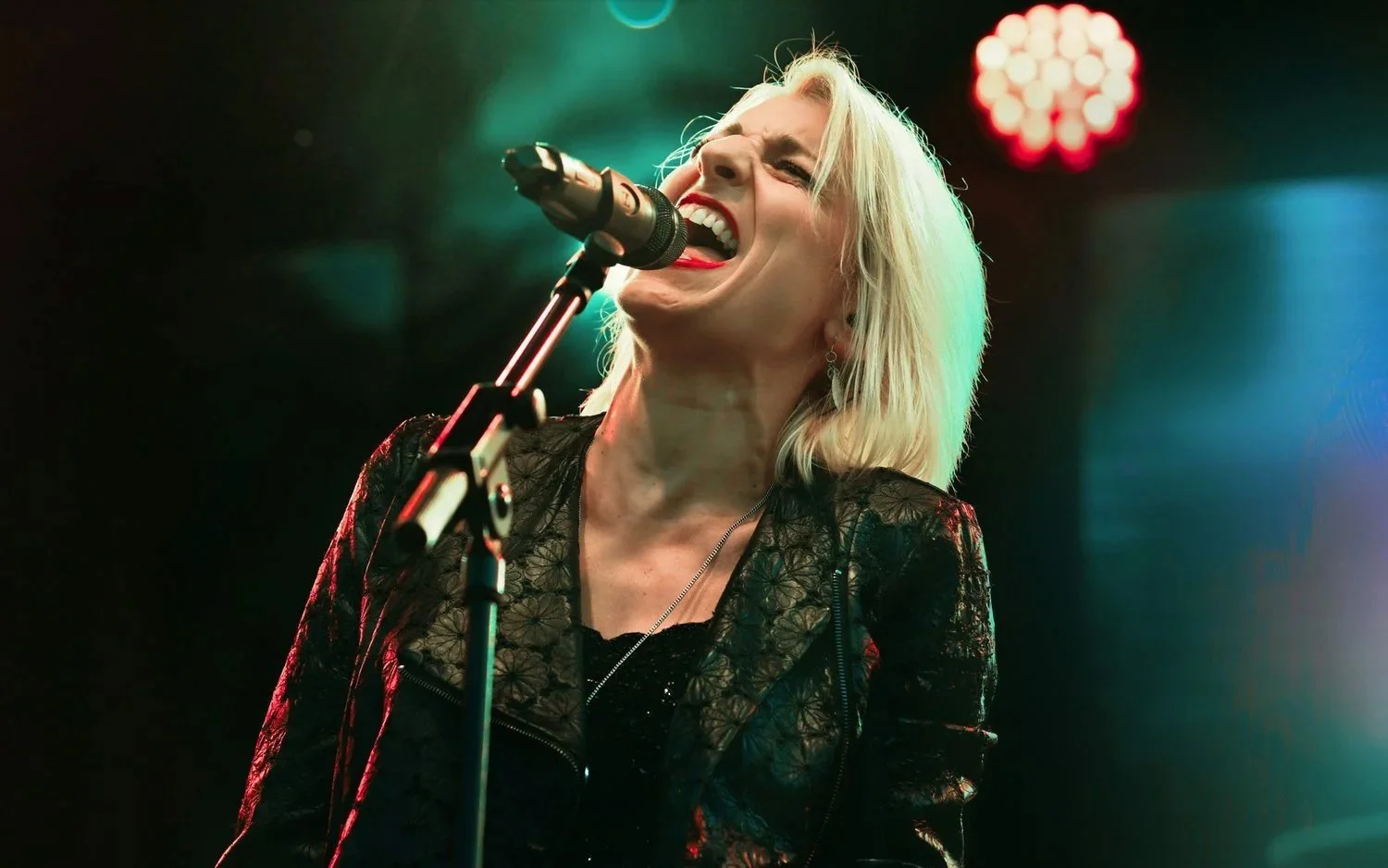Chanteuse en pleine performance, intensité vocale et énergie live captées.