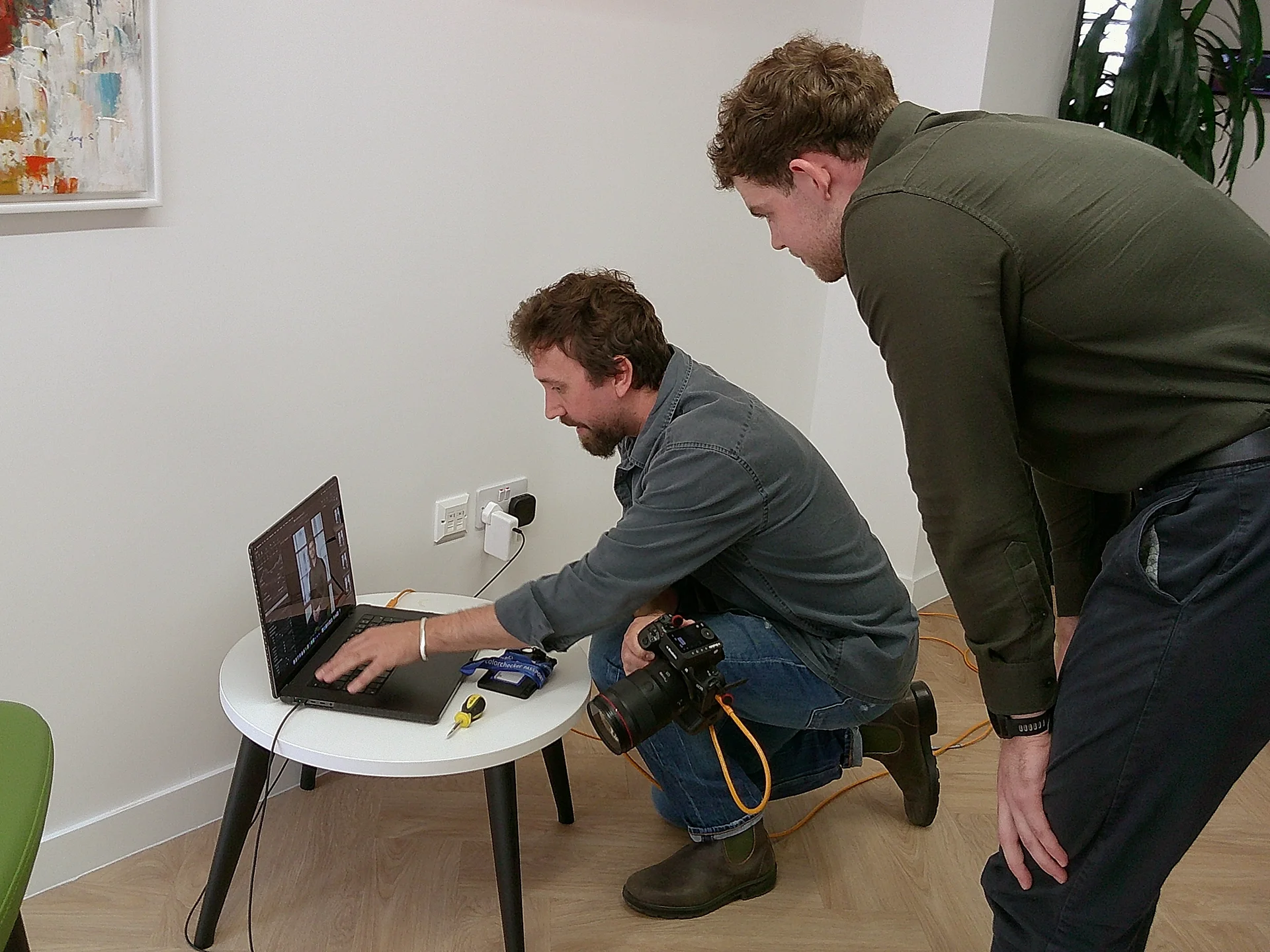 Photographer and client collaborating over laptop during tethered corporate shoot on set