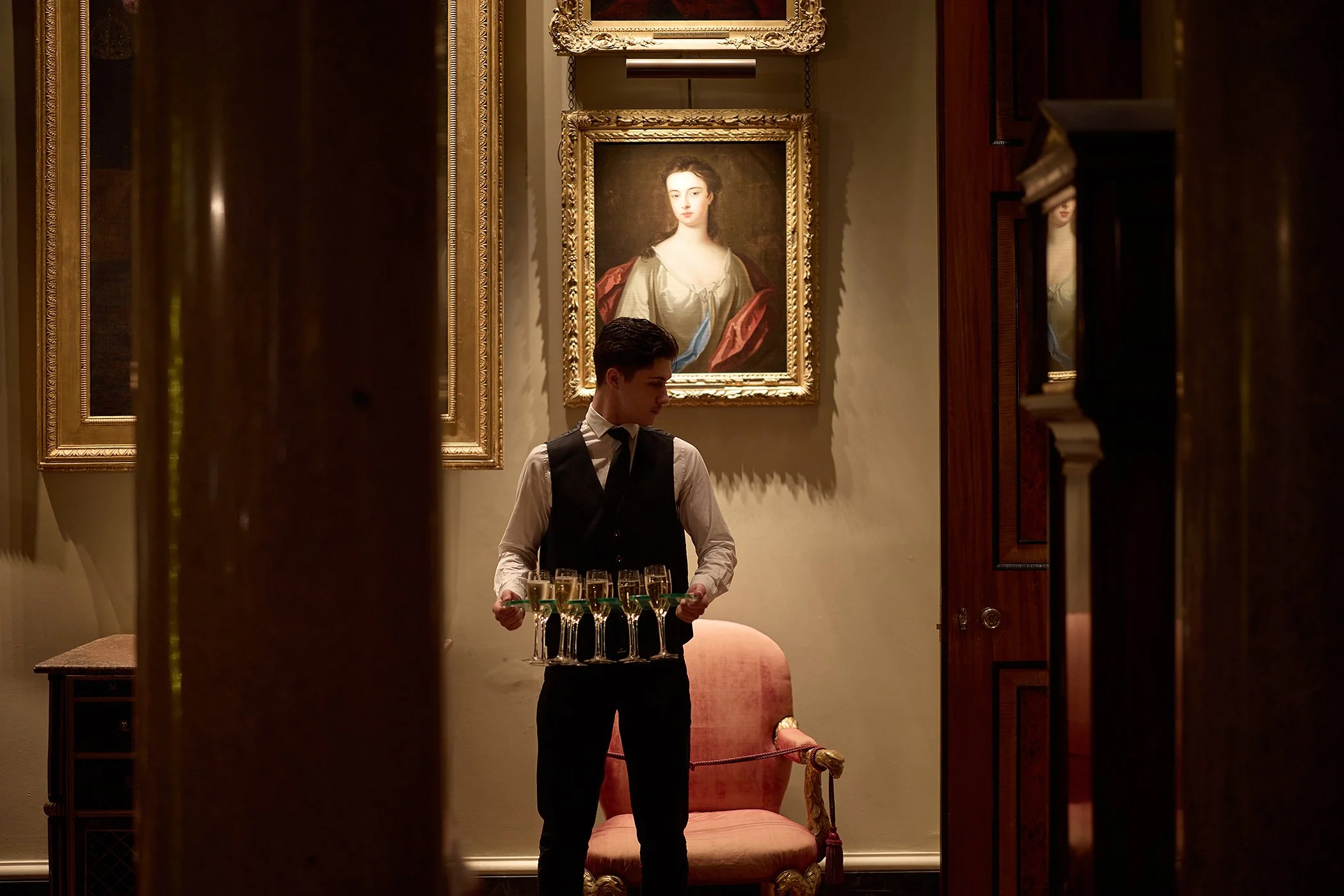 Candid event photography of a waiter serving champagne at the high-end Goodwood GRRC Ball in Chichester, capturing authentic luxury hospitality for marketing assets.