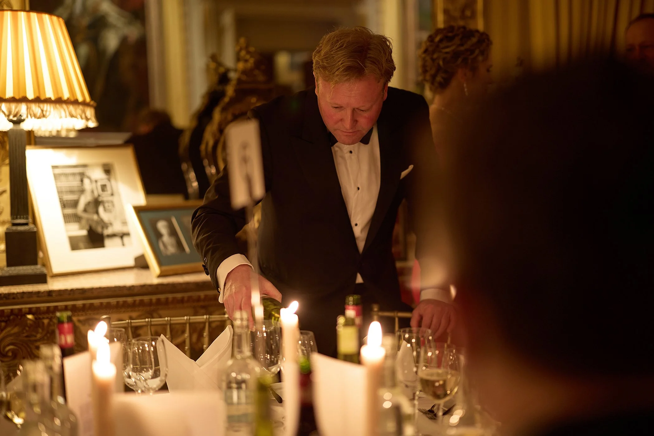 Candid photography of a man pouring wine at a black-tie dinner table during the high-end Goodwood GRRC Ball, capturing authentic luxury hospitality and event branding.
