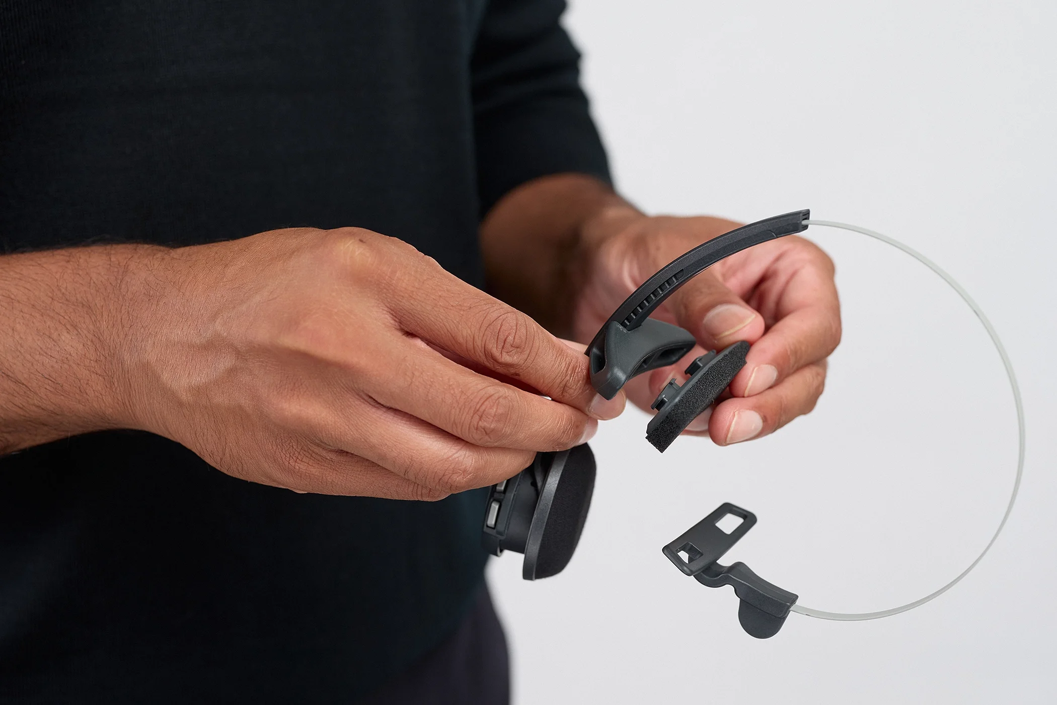 Hand model holding a VoCoVo headset on a white background in a professional product photography studio.