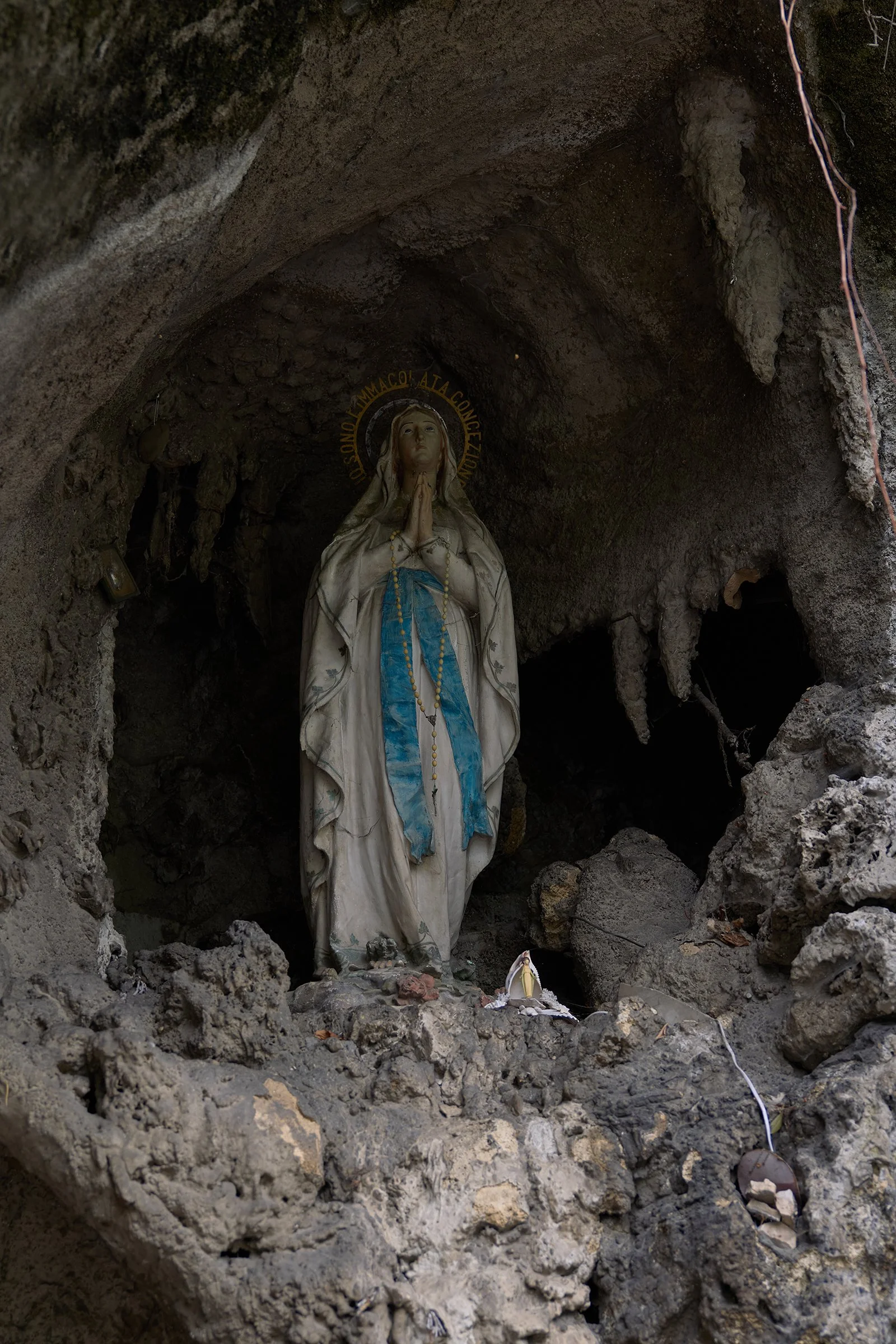 Religious statue of Virgin Mary inside a rocky cave.