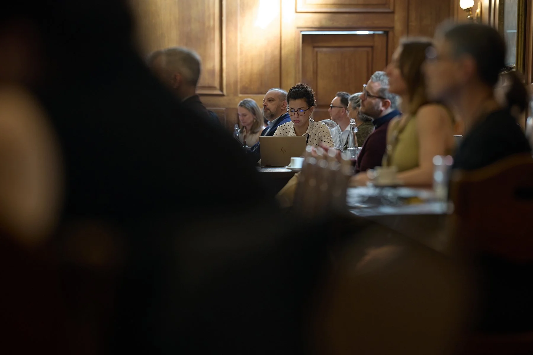 Candid corporate photography of a delegate taking notes during a keynote at the IHP World Health Summit in London, capturing authentic business engagement and focus.