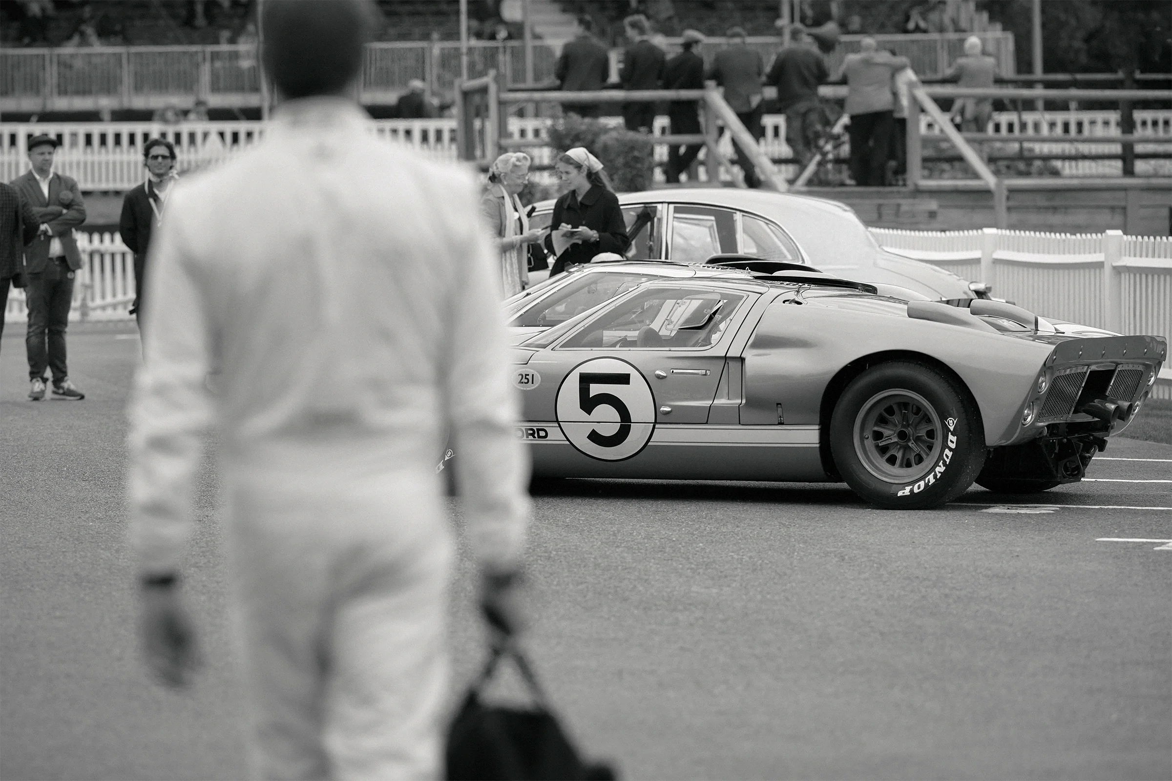 Scott Dixon walking beside a Ford GT40 on track at the Goodwood Revival