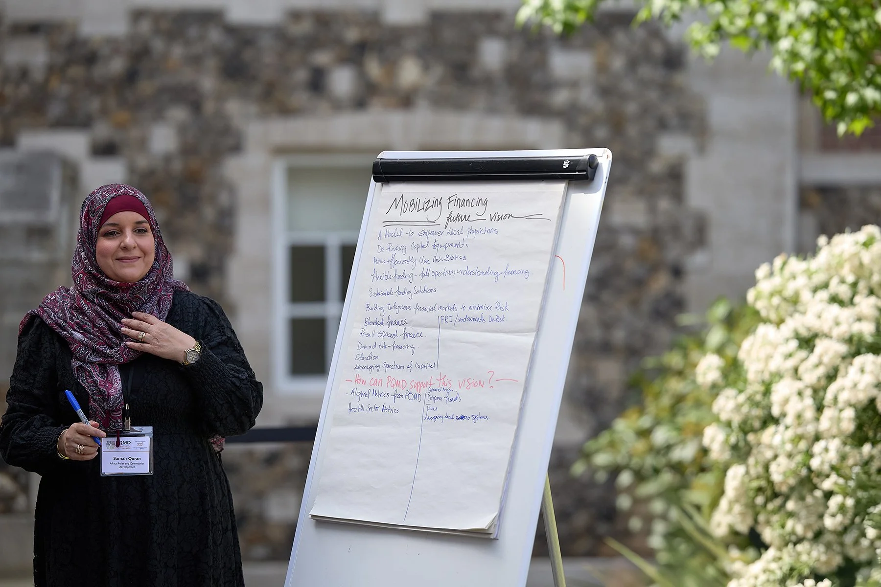 Aleena Khan, Global Health Policy professional, making notes on a whiteboard during the IHP London Summit, capturing authentic collaboration and strategy.