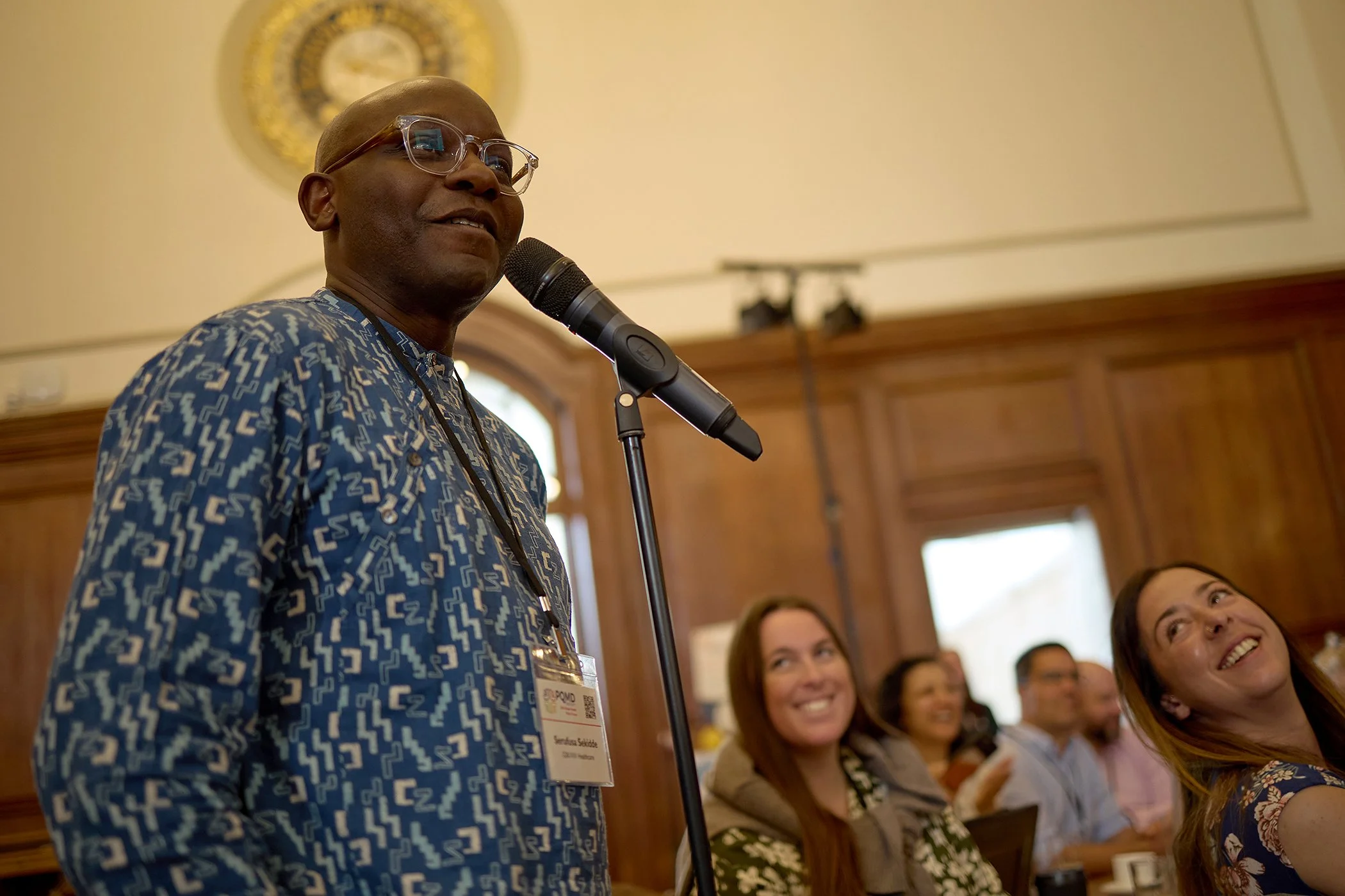 Candid photography of an attendee asking a question during a Q&A session at the IHP PQMD Global Health Policy Forum in London, capturing authentic corporate engagement.