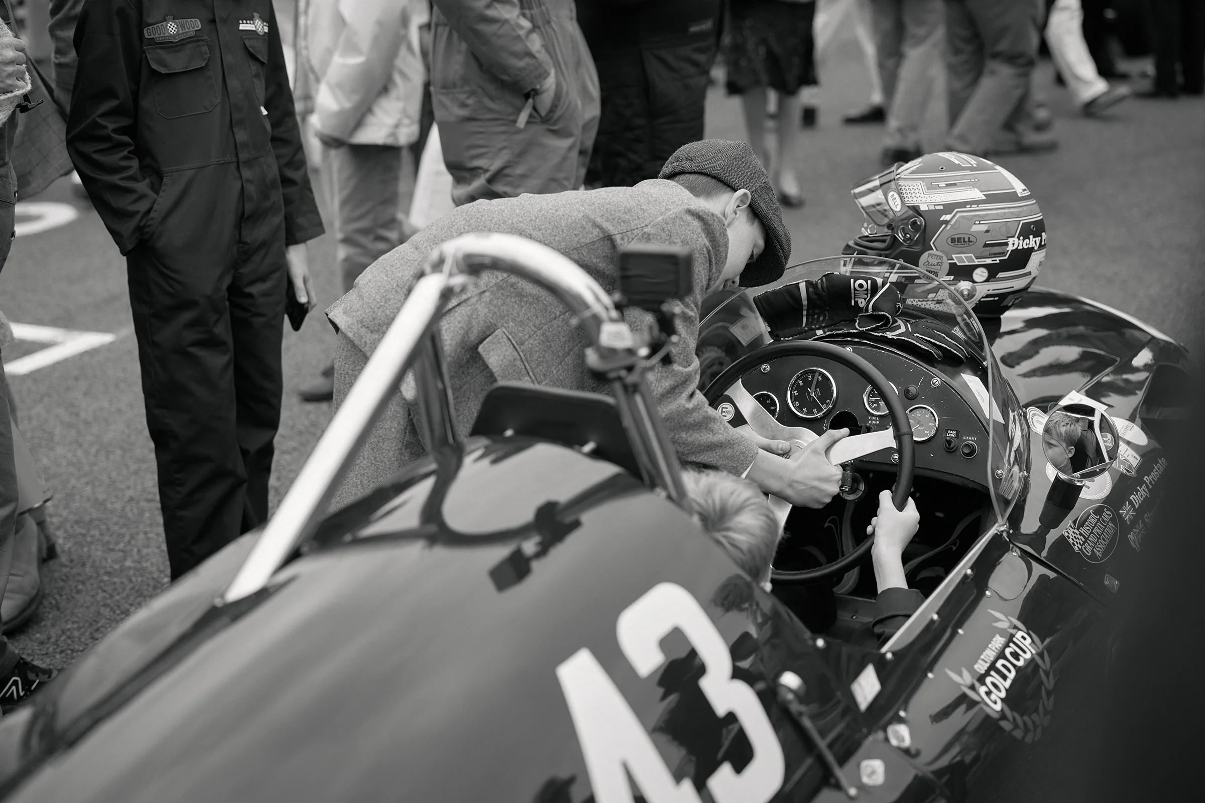 Two young boys assemble the steering wheel of a vintage racing car on the start line at Goodwood Revival 2026