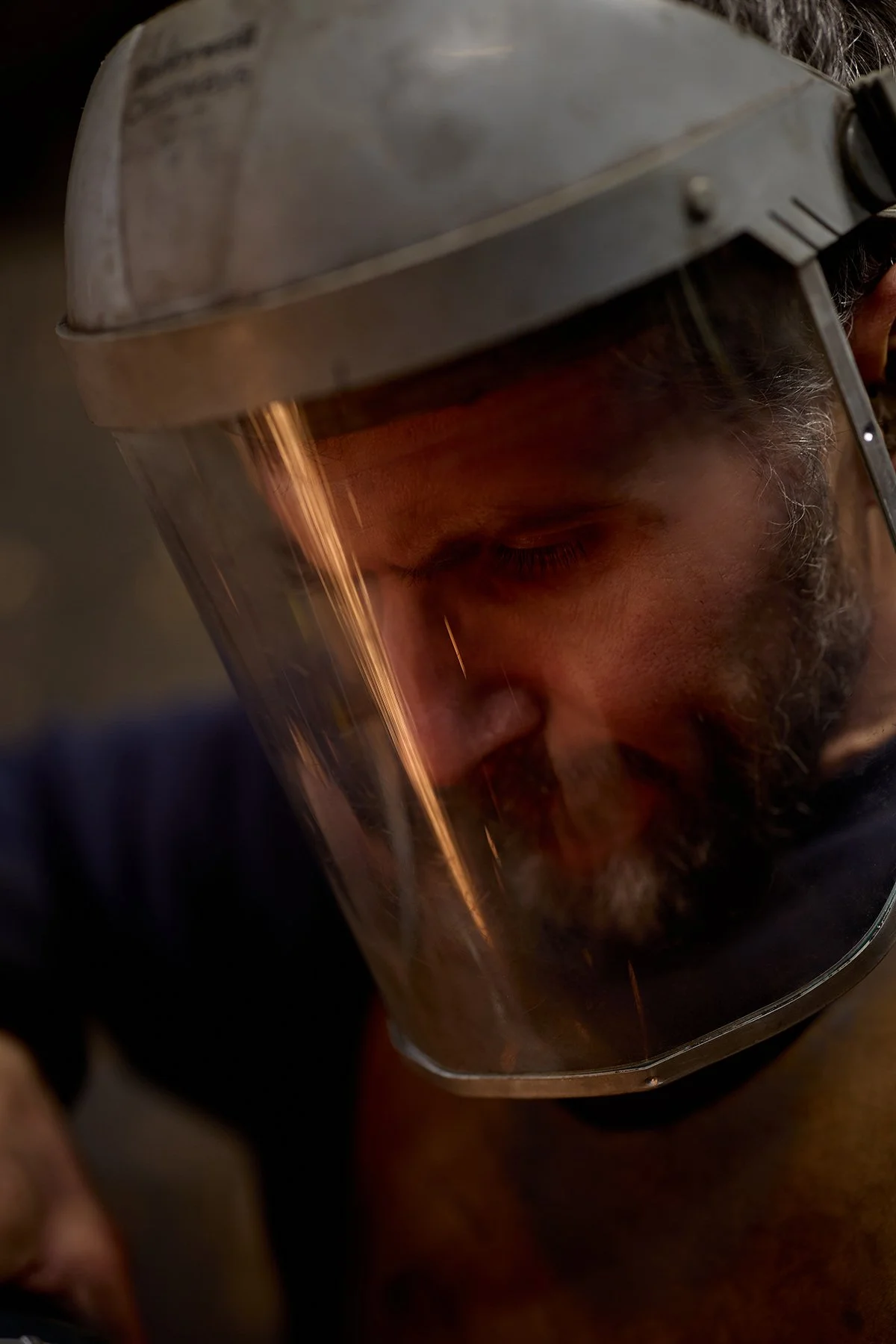 A man wearing a welding helmet with the visor down, engaged in welding.