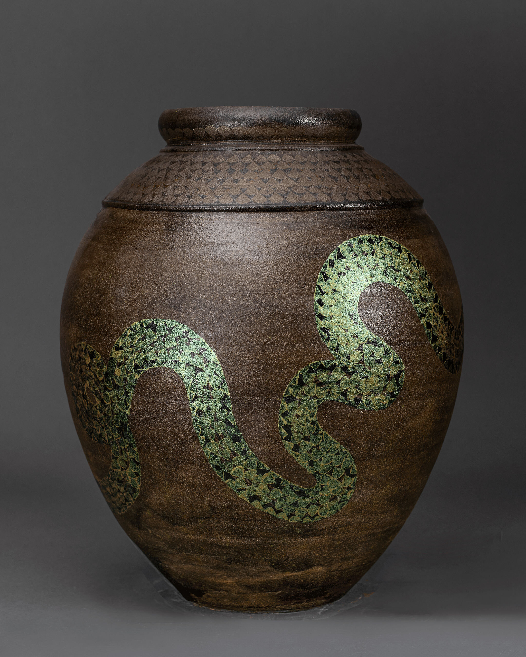 Brown clay vessel featuring winding green snake pattern