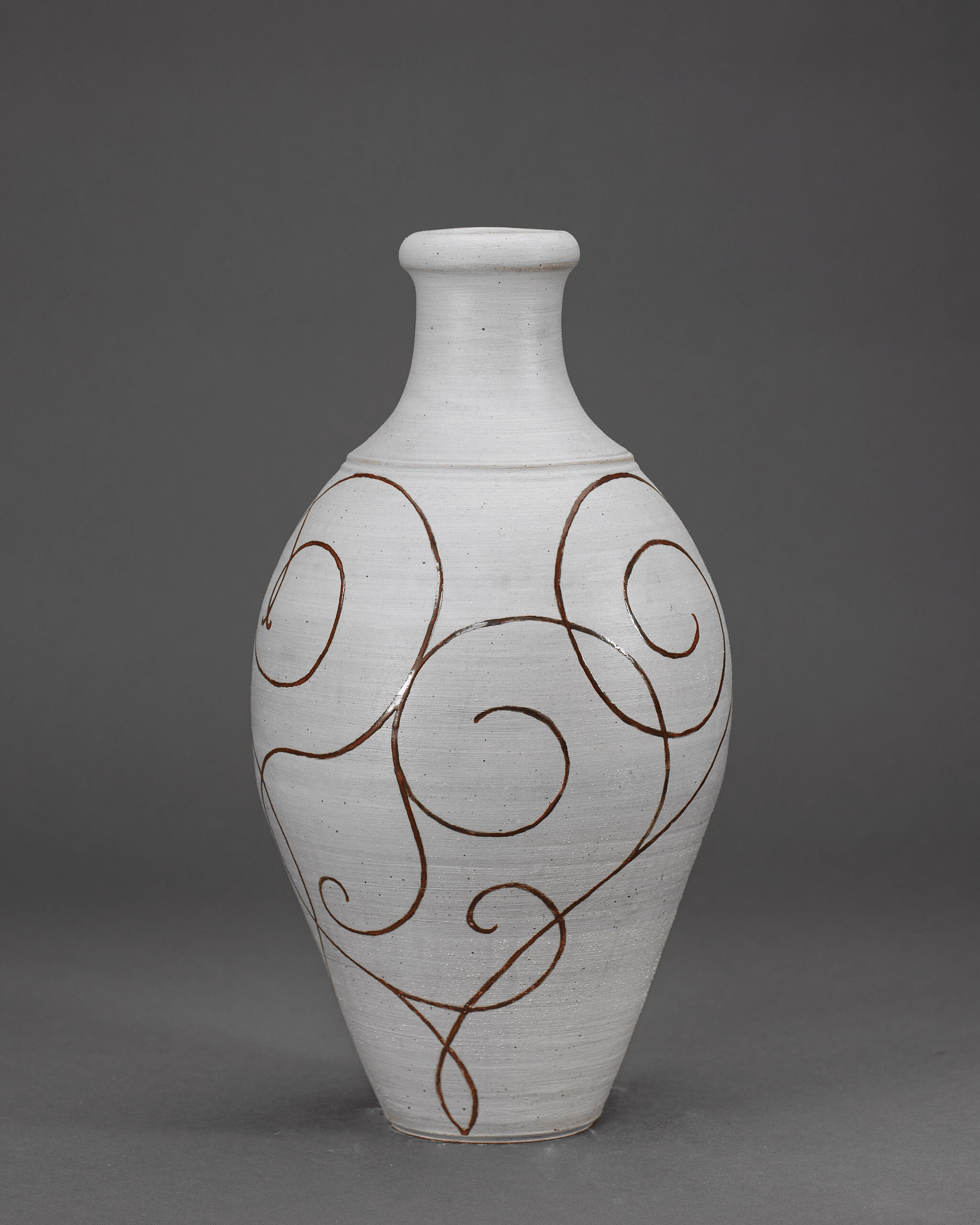 White pottery vase decorated with bold red swirl designs