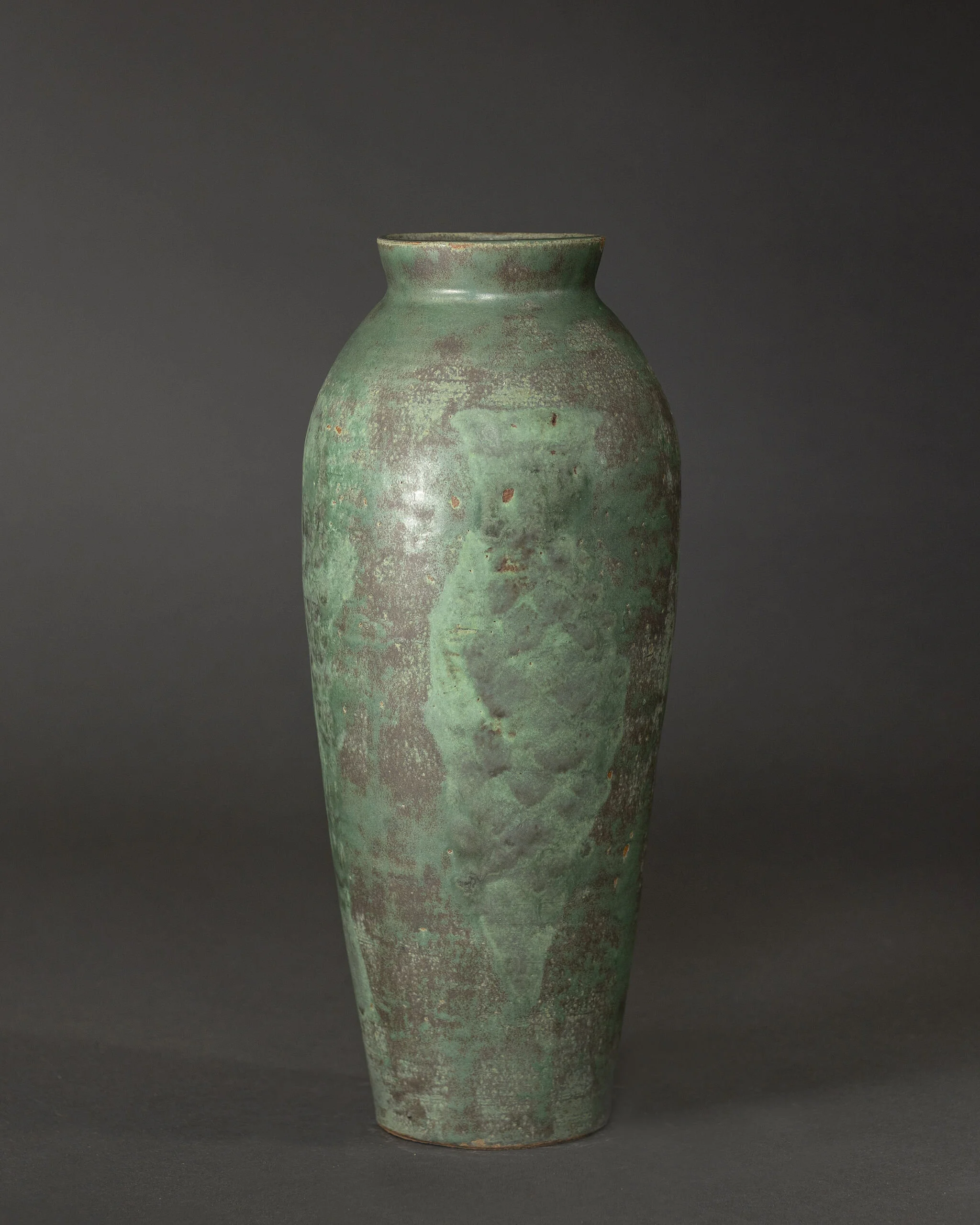 Green pottery vase showcasing mottled patina texture and earthy tones