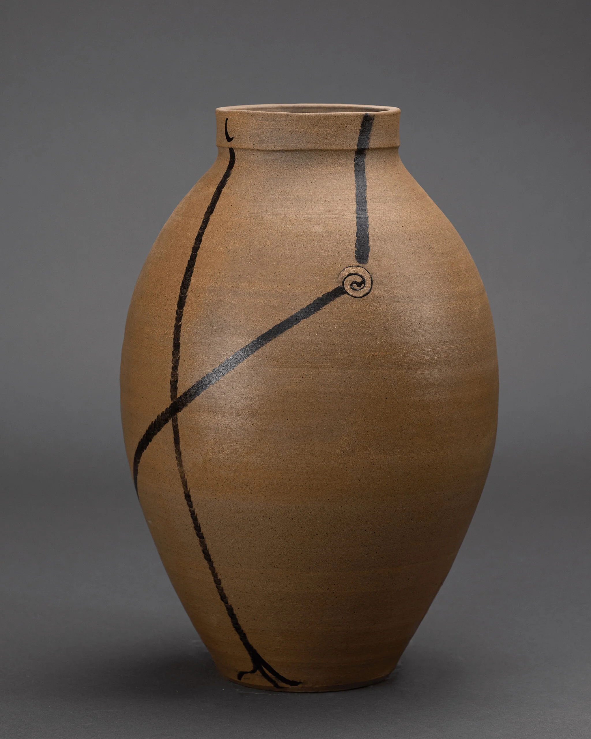 Tan ceramic vase adorned with flowing black curved line motifs