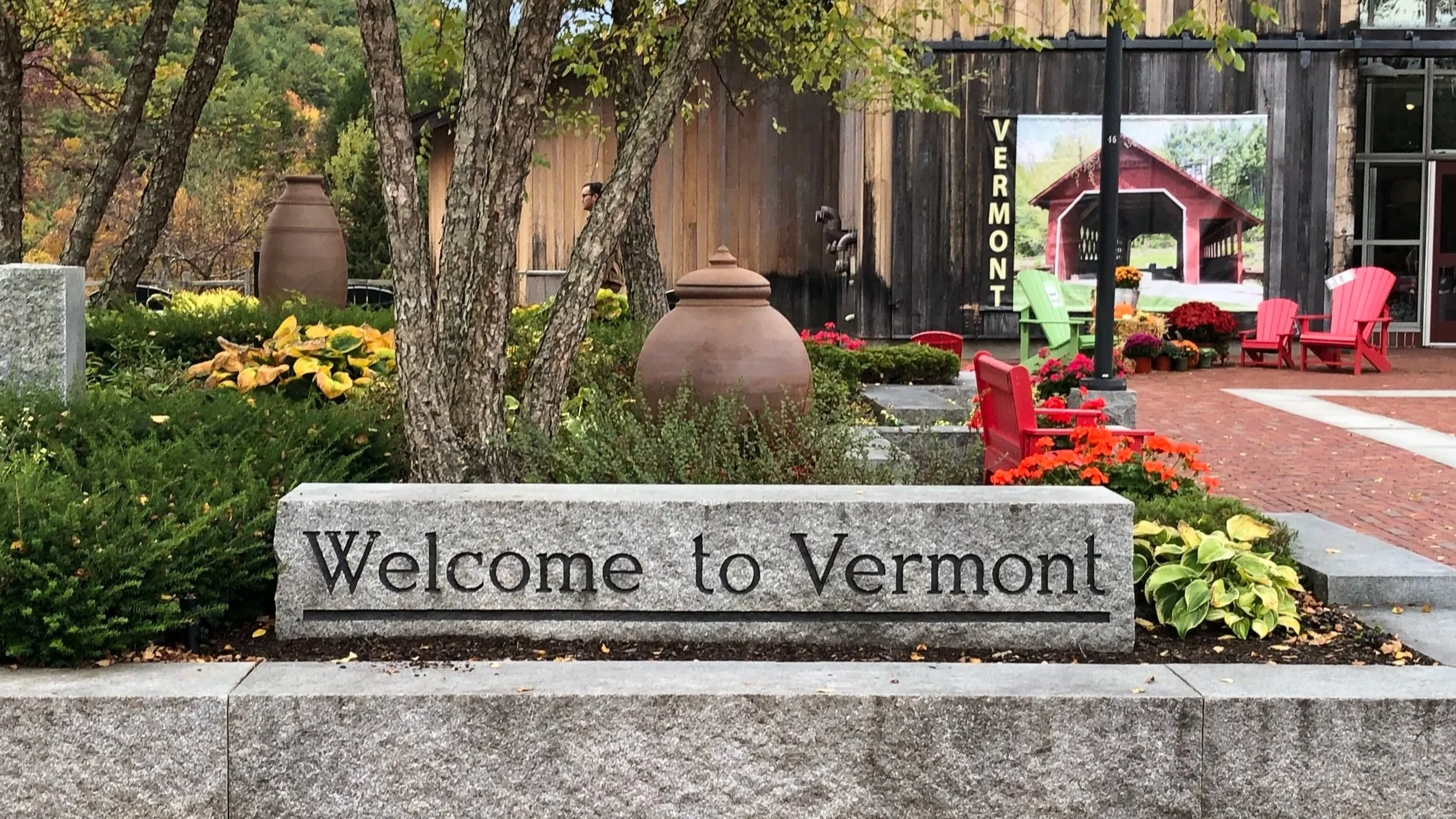 Scenic Vermont Welcome Center garden with colorful flowers, pottery, and Adirondack chairs.
