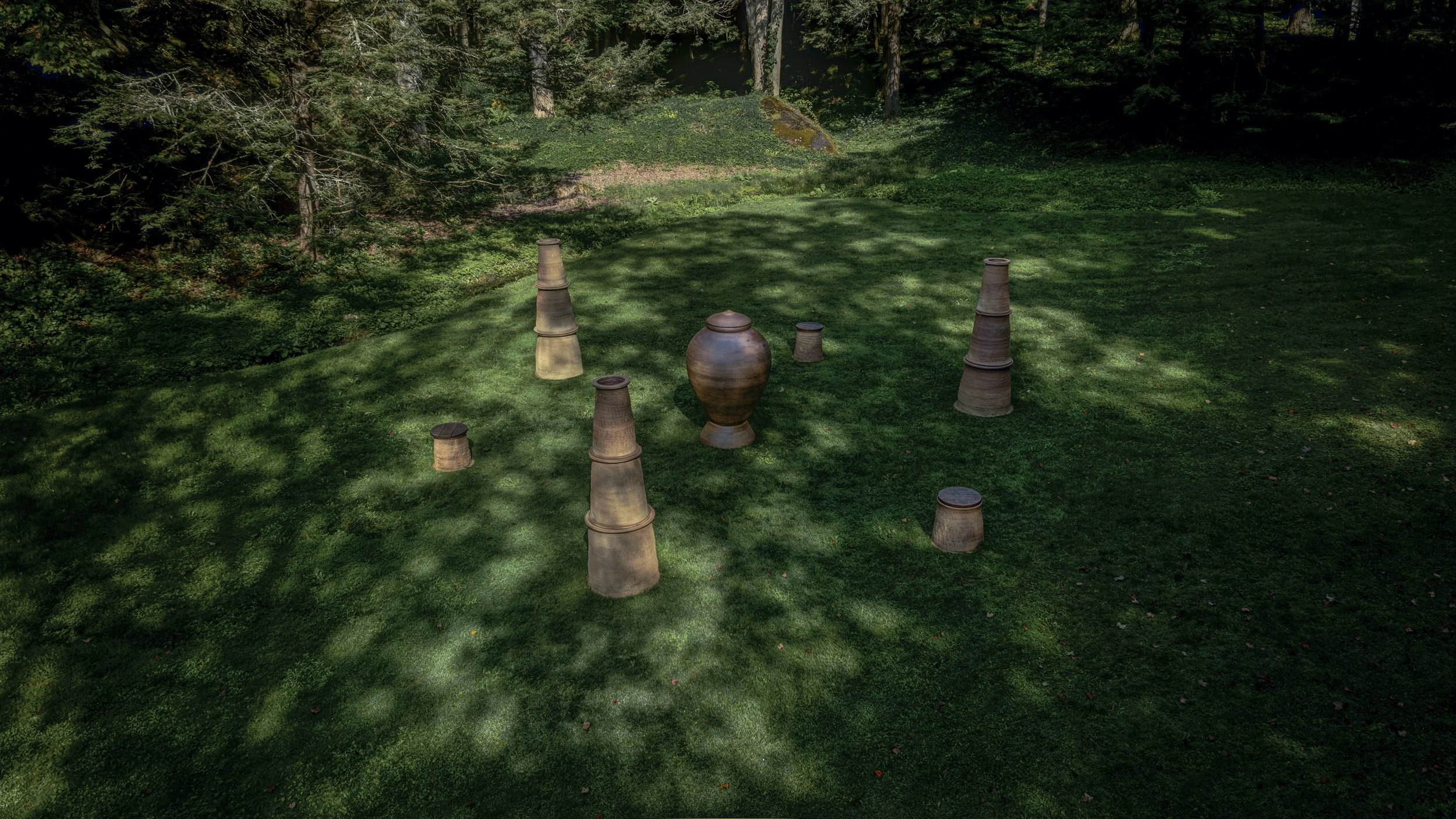 Ceramic art pieces blending with garden landscape of trees, grass, and dappled sunlight