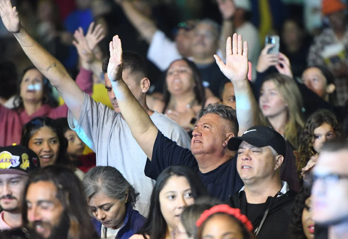   Crowd worships under the evening sky  