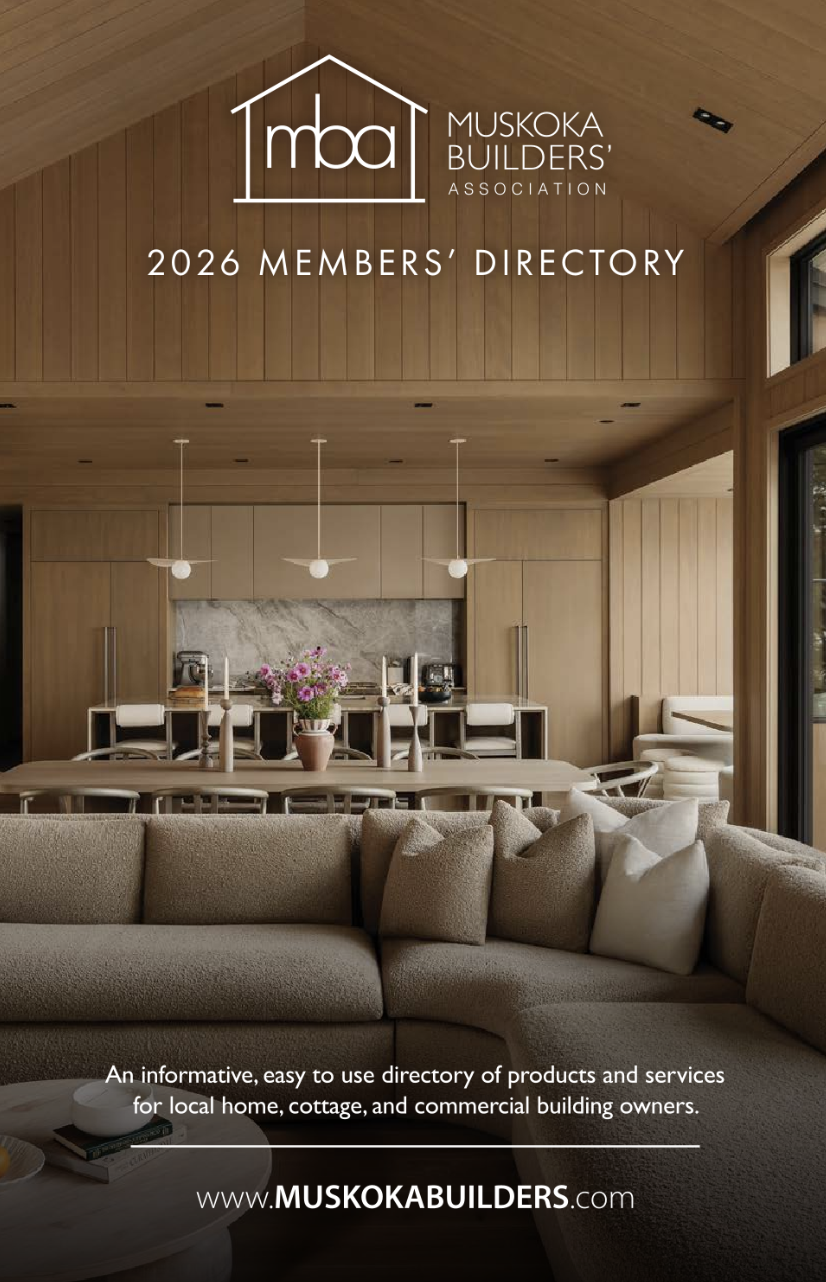 Interior of a modern home with wood paneling, a beige sectional sofa, and a dining area with a vase of pink flowers, pendant lights, and kitchen appliances in the background.