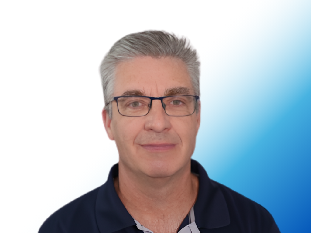 A man with gray hair, glasses, and a slight smile wearing a navy polo shirt against a white and blue gradient background.