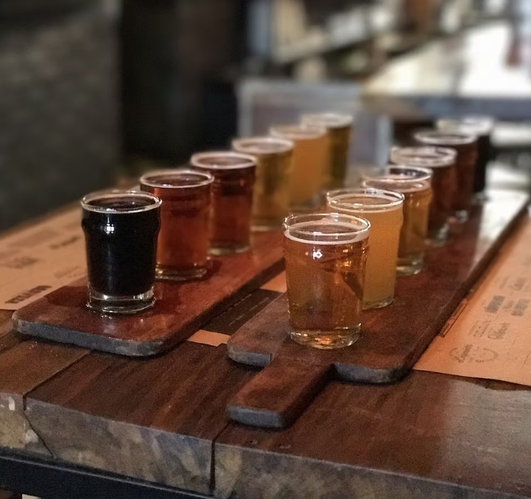 Two wooden flight boards holding small glasses of various beers.