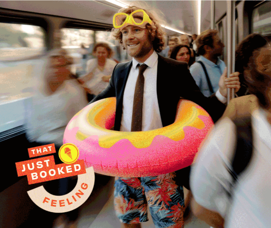 A man on a train wearing sunglasses, a suit with a tie, and colorful shorts, holding a pool float around his waist, with other passengers in the background.