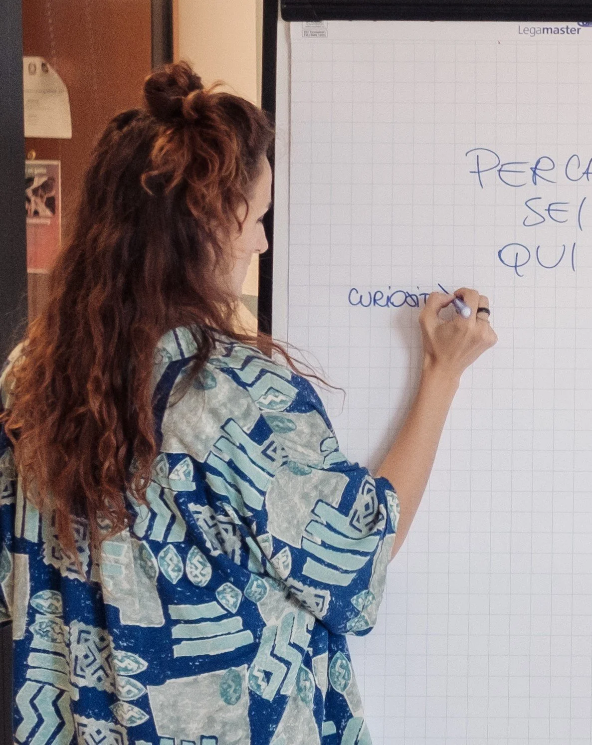 Persona che scrive su una lavagna a fogli mobili con un pennarello.