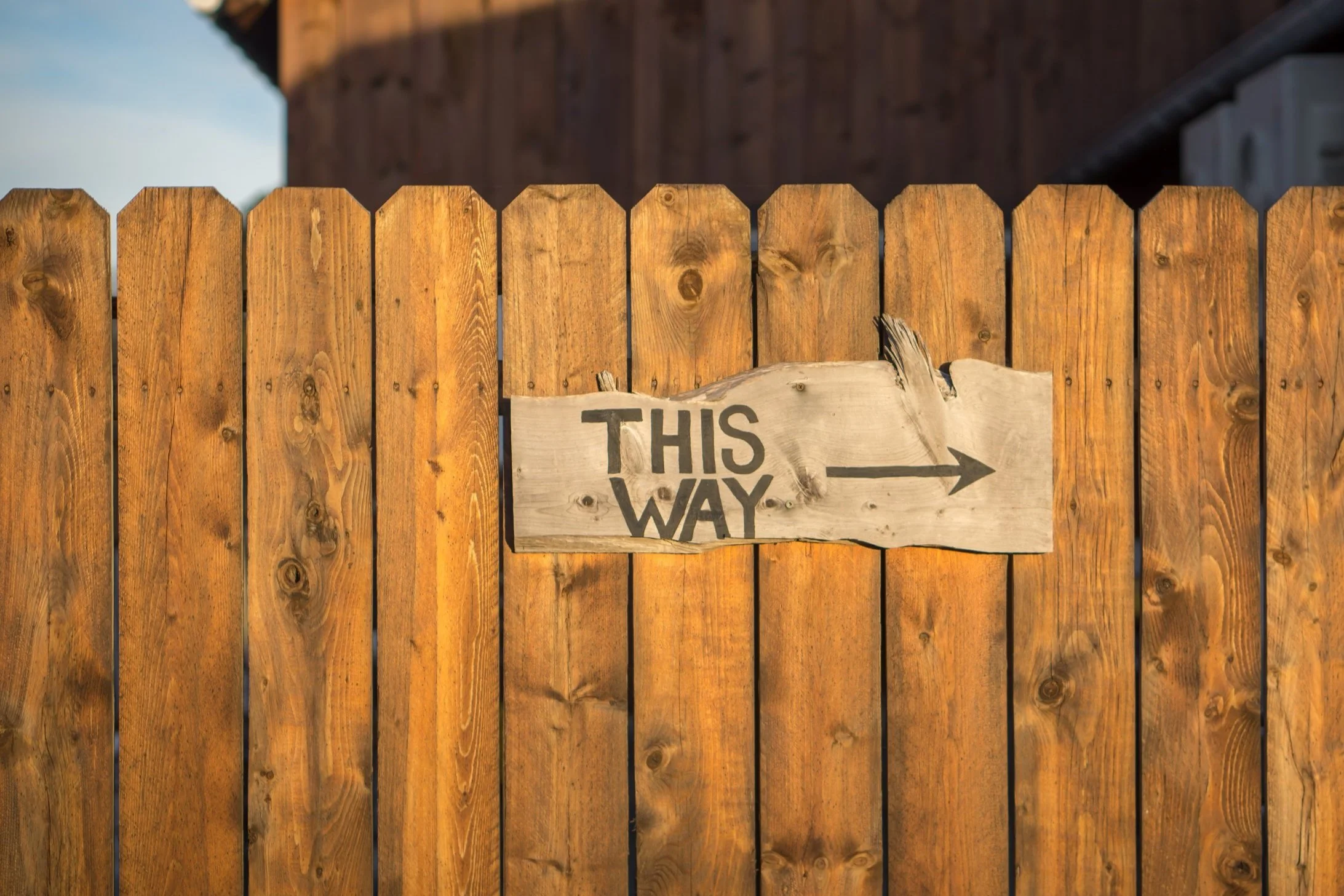 Cartello di legno "This Way" su una staccionata di legno.
