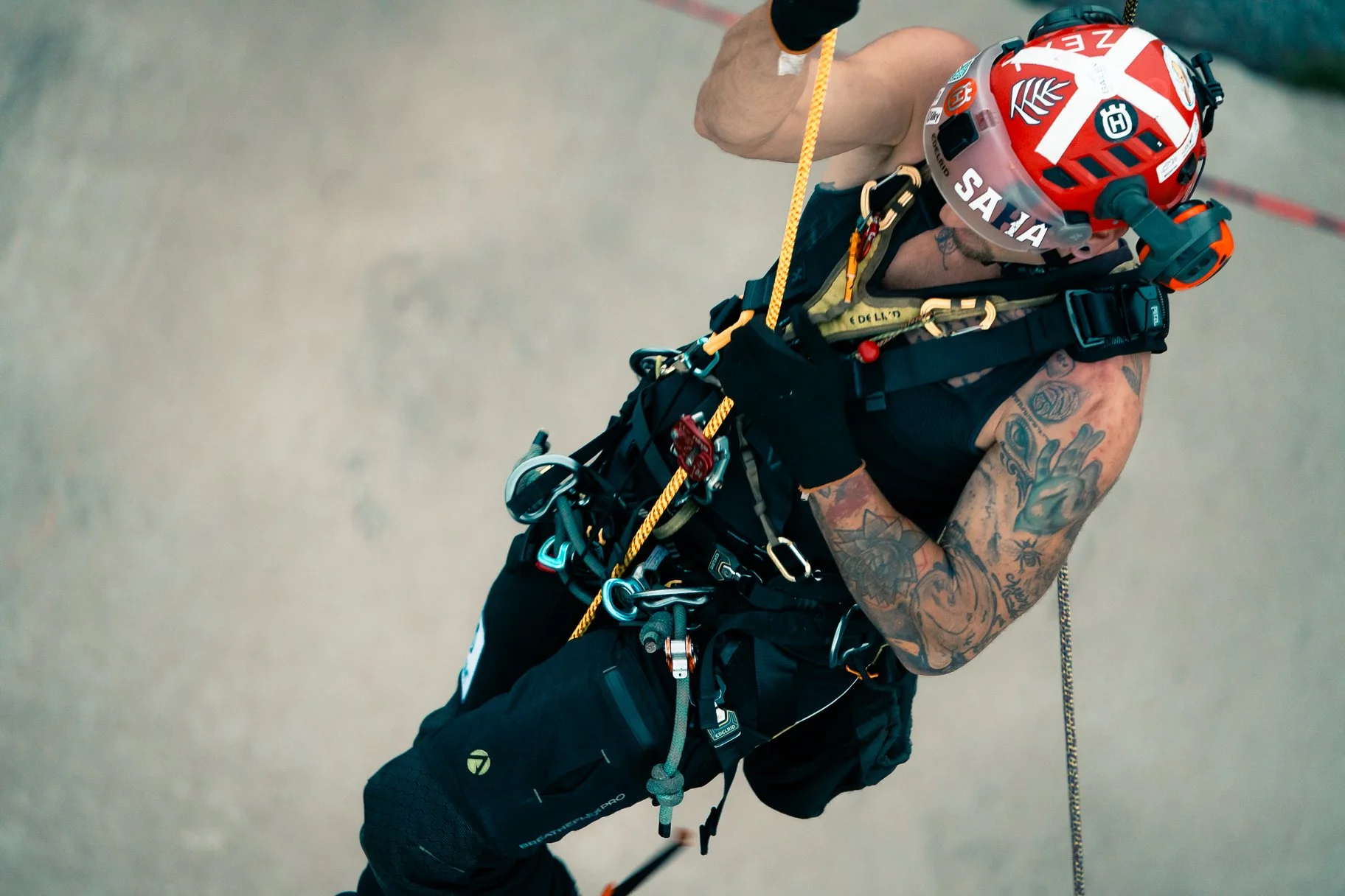 Climber wearing a red helmet and black climbing gear, preparing for a climb on a concrete surface.