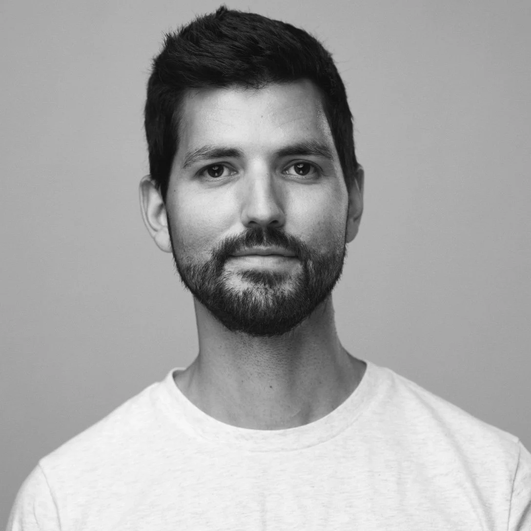 Black and white headshot photo of a man on a gray background.