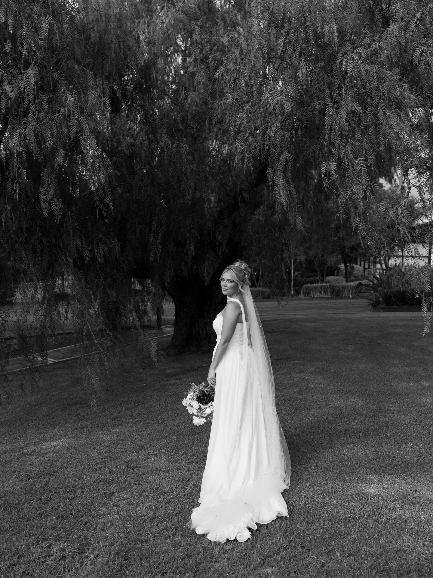 A wedding dress doesn&rsquo;t carry itself.

It takes hands. Patient ones. The kind that belong to people who&rsquo;ve known you long enough to kneel in the grass without being asked, who fix the veil between frames because they can&rsquo;t help it, 
