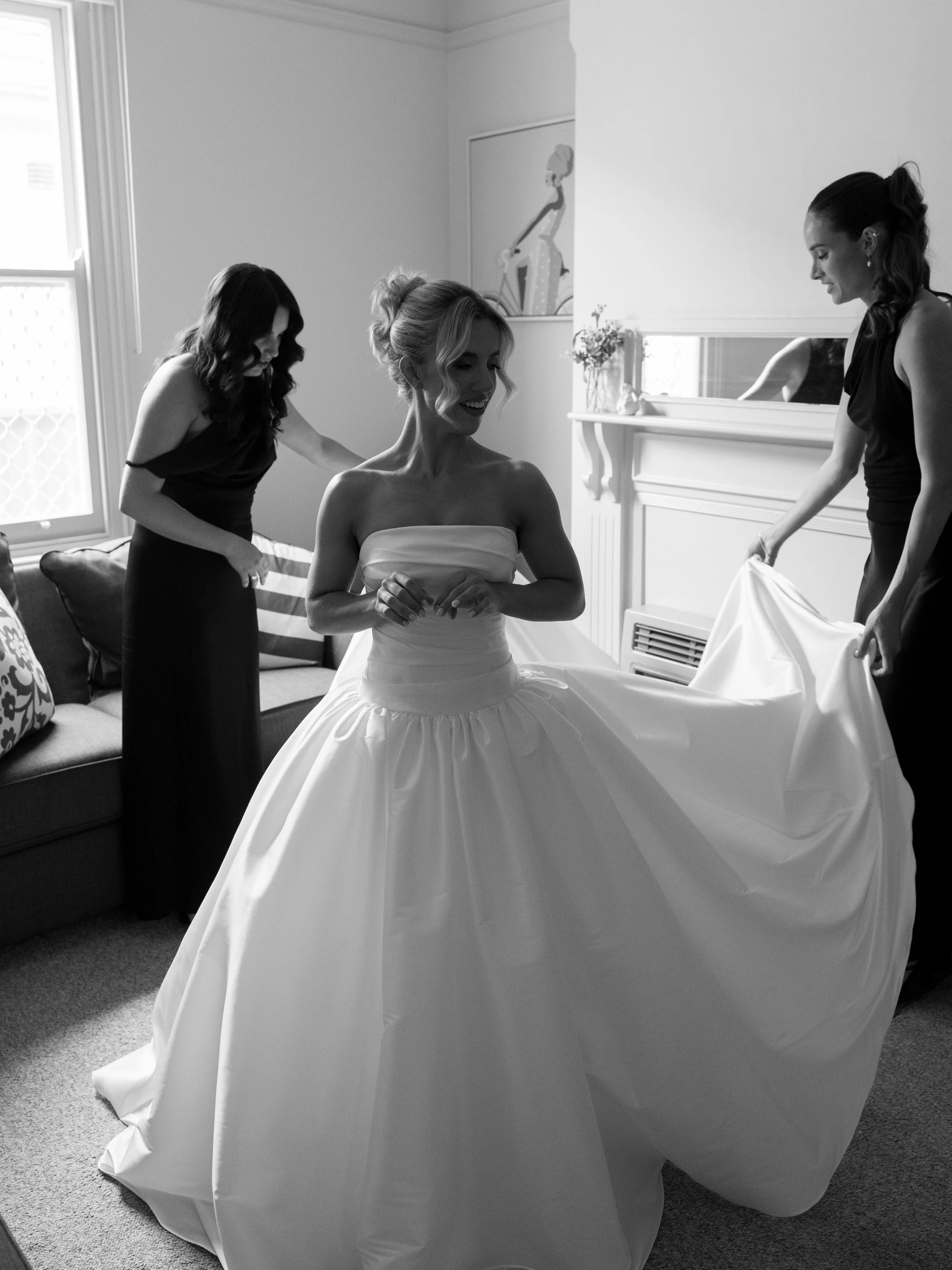 It&rsquo;s never just the bride getting ready. It&rsquo;s a room full of hands doing small jobs nobody assigned them.

One doing up the buttons. One holding the train off the floor. One just standing close, watching, ready to move the second she need