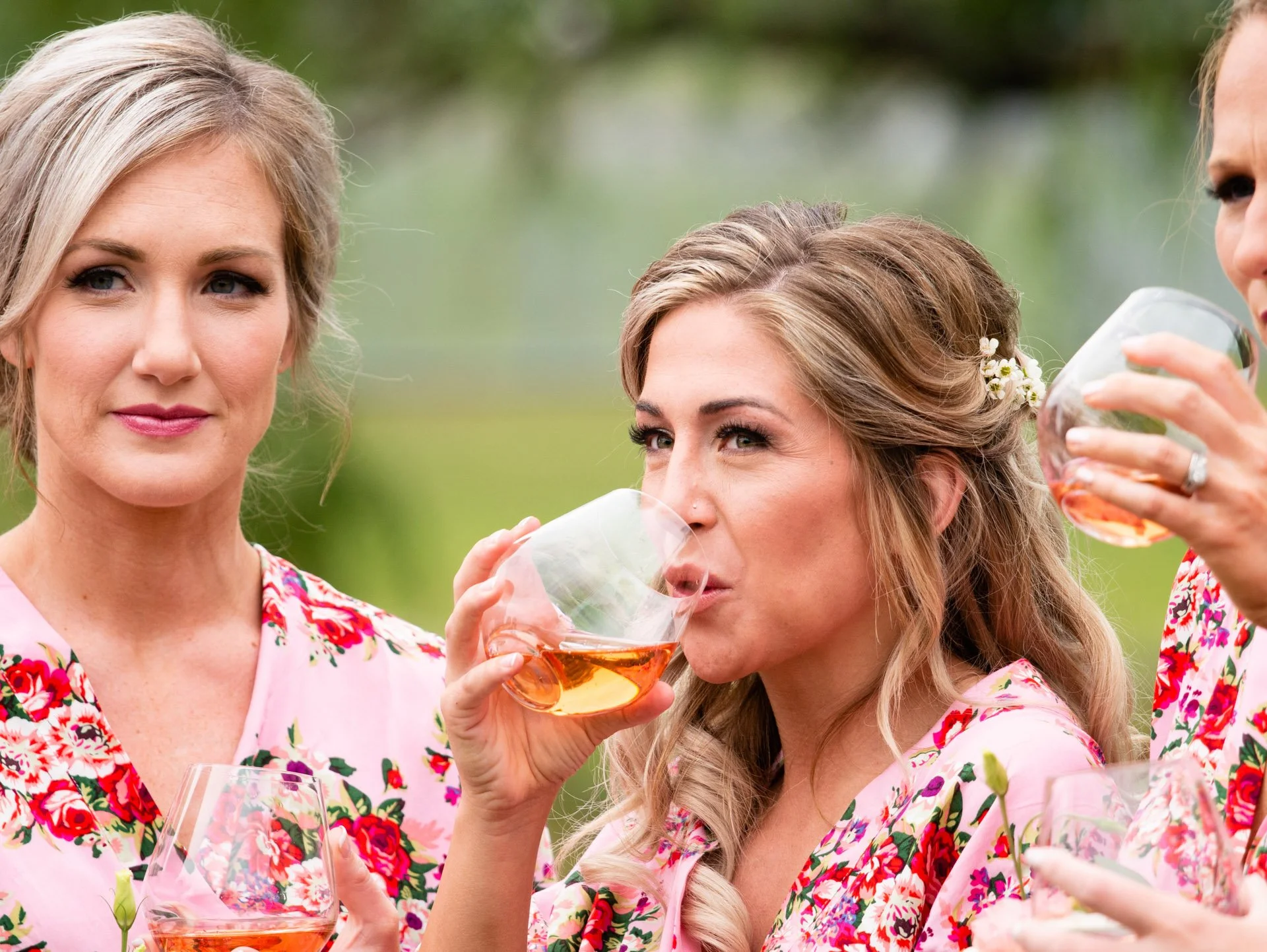 Women in floral dresses enjoying drinks outdoors at a gathering or celebration.