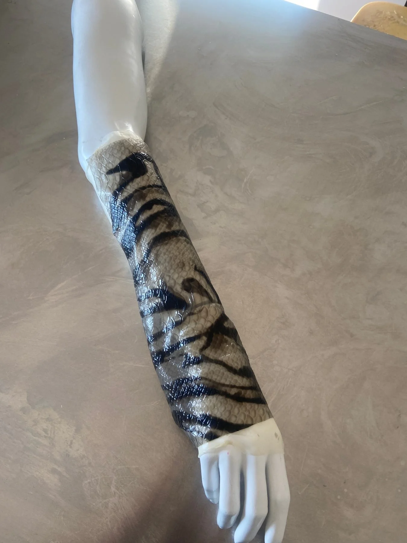 Translucent snake skin latex with black markings applied to a sculptural arm form by Janine Grosche / PATH