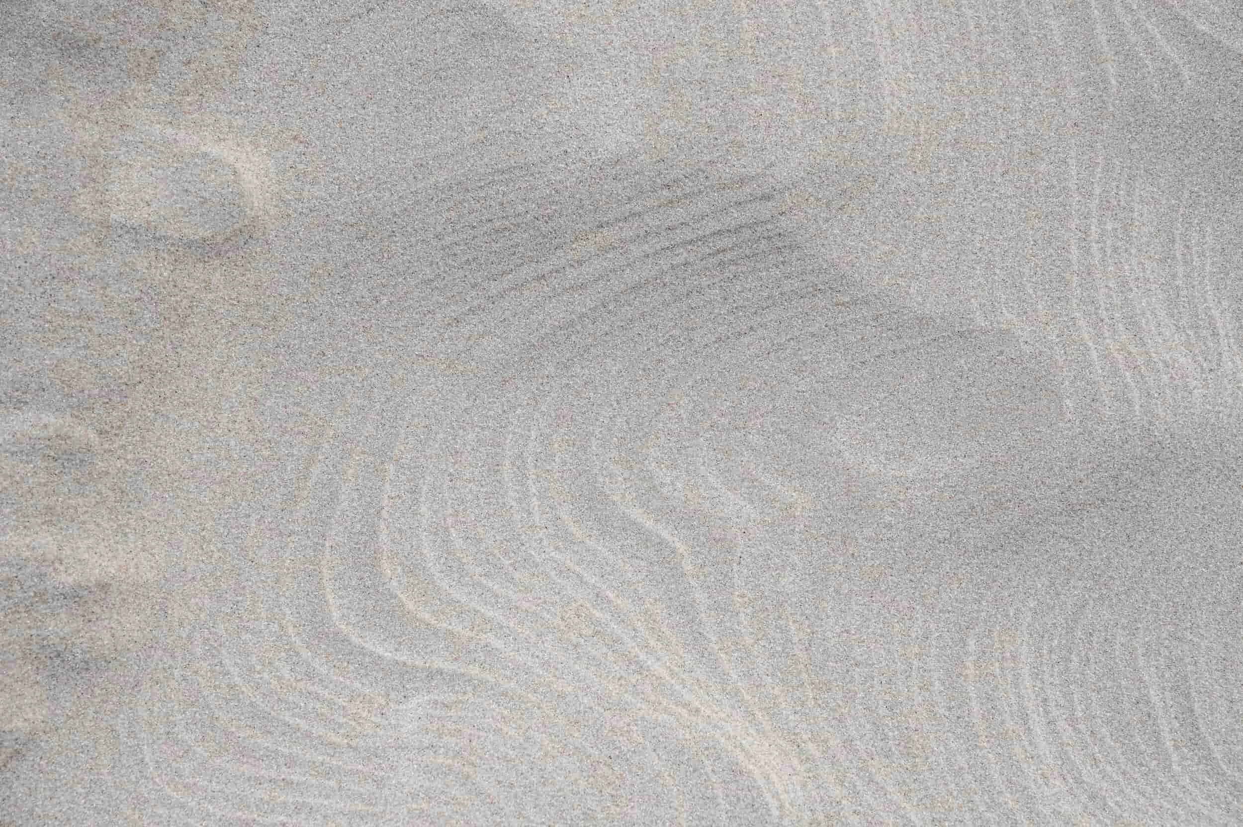 Close-up of textured sandy surface showing natural patterns and small grains of sand.