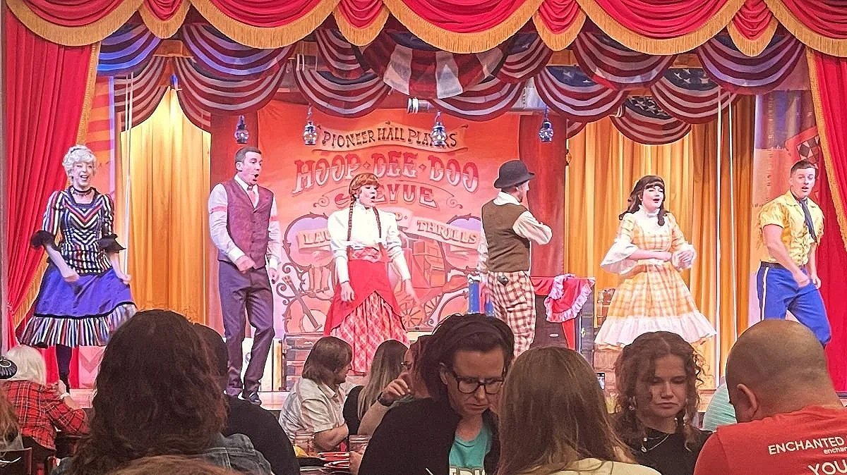 The six main actors on the stage in colorful western outfits at Hoop Dee Doo Musical Revue at Fort Wilderness in Disney World. A great restaurant for kids.