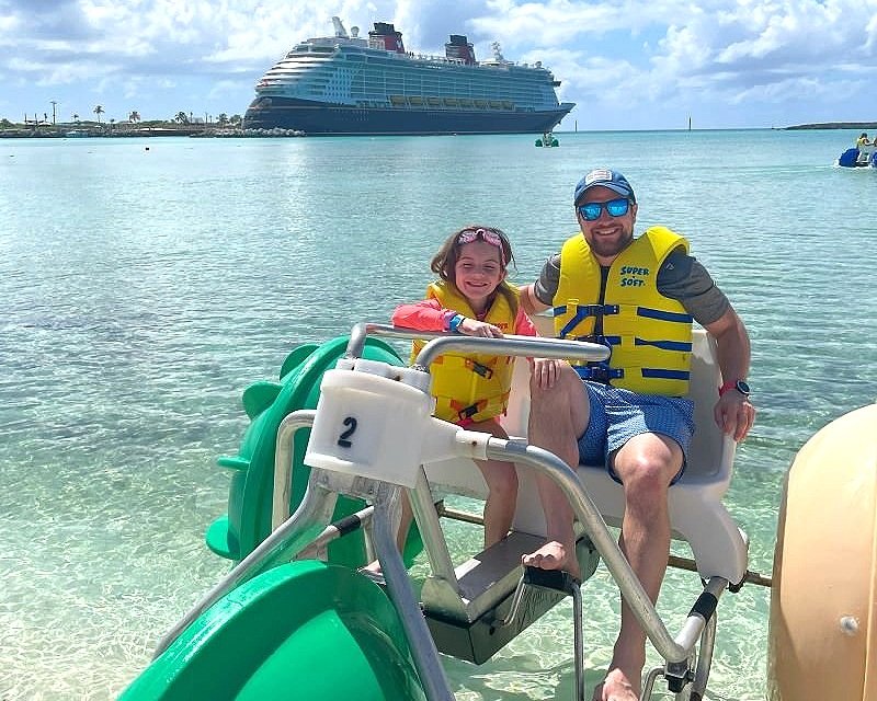 My daughter and I on an aqua trike on castaway cay with the disney fantasy in the background